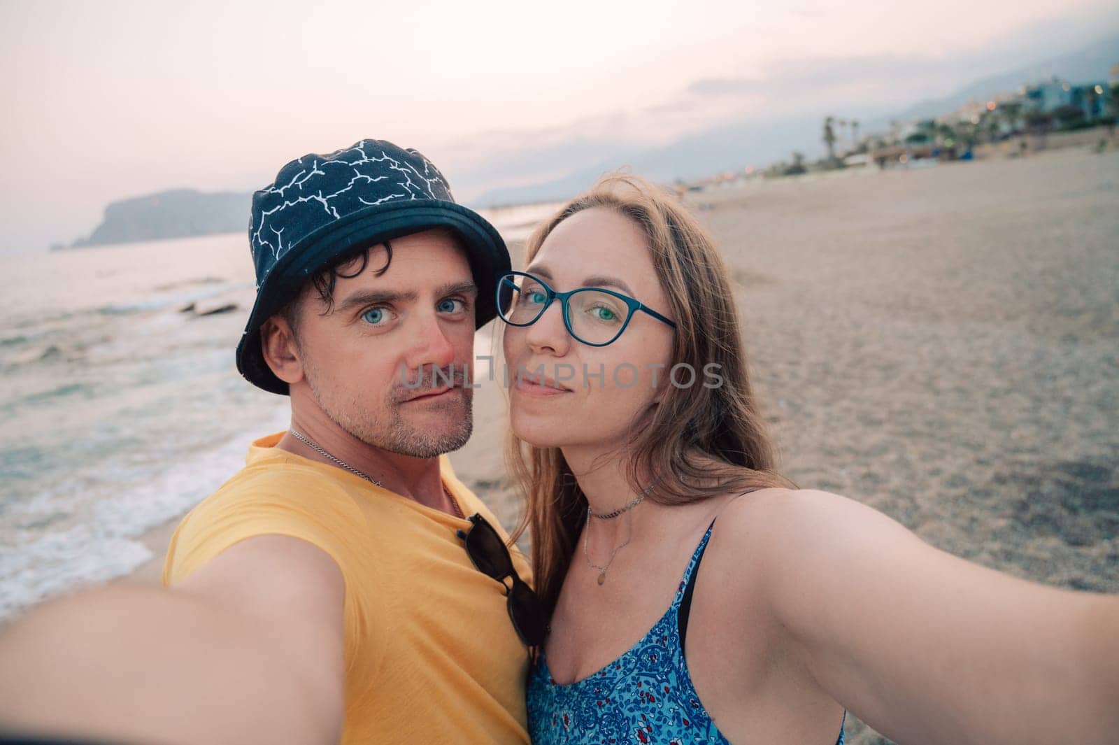 Happy couple taking a photo on a beach at the sea in Alanya city, Turkey. Travelling or vacation concept