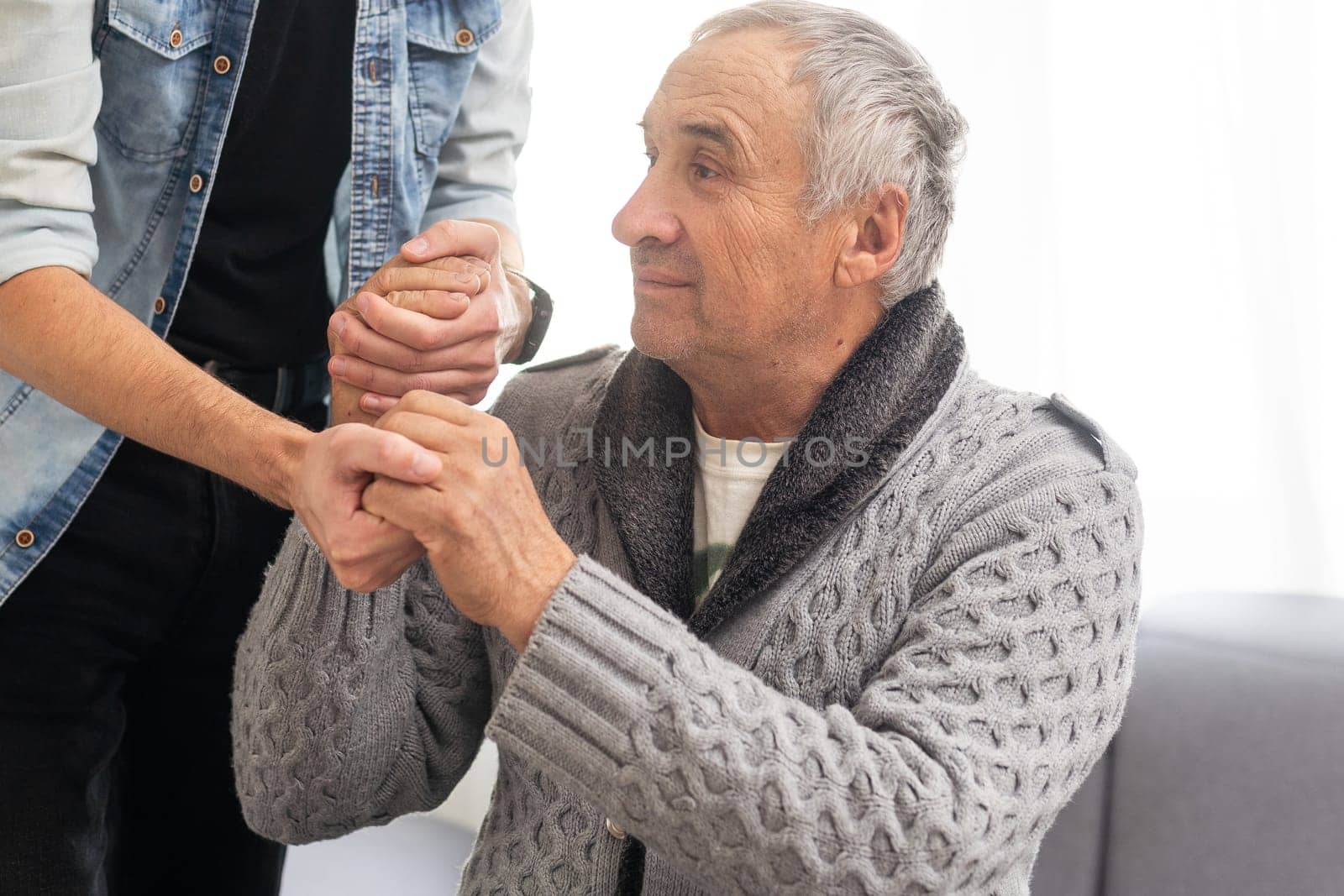 Grown up son asking for apologizes to offended stressed elderly senior daddy, sitting together on couch. Compassionate young man supporting, giving psychological help to frustrated middle aged father. High quality photo