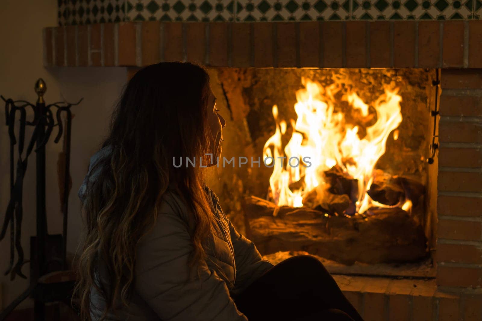 latin woman sitting in front of the fireplace in the cold winters, engrossed in the flames