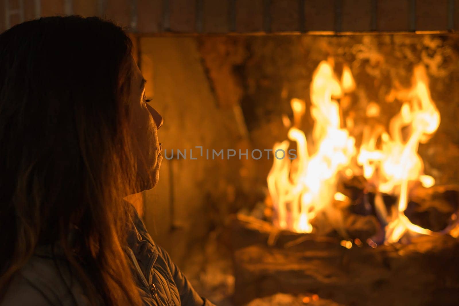 latin woman in front of the fireplace, in a moment of relaxation and peace during the harsh winter days in europe.