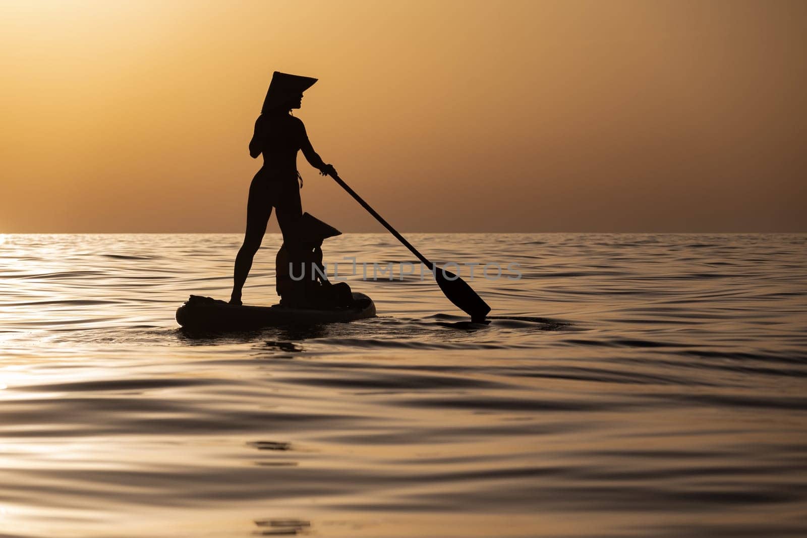 a woman with a child on a sup board in the sea swim against the background of a beautiful sunset, Standup paddleboarding by Rotozey