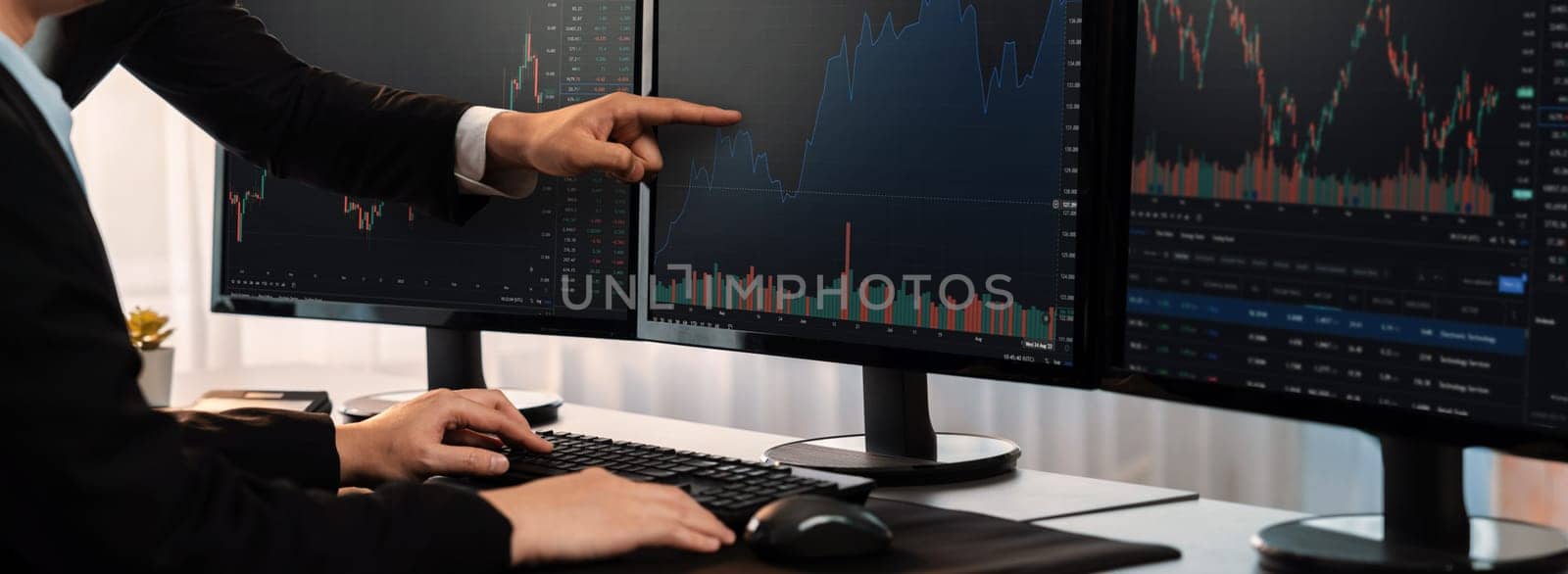 Group of traders discussing on office desk, monitoring stock market on monitor at office workplace. Businessman and broker analyzing stock graph together at stock trading company. Trailblazing