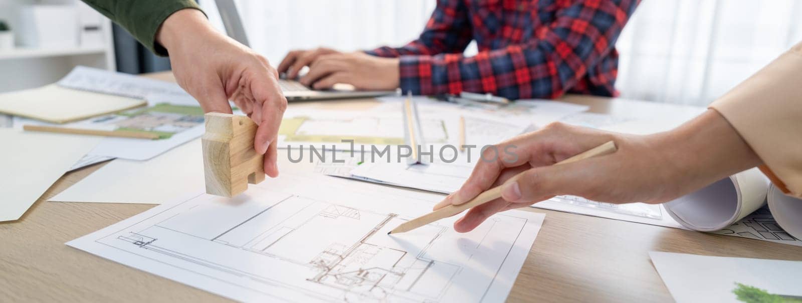 Skilled architect team using architectural equipment during colleague discussion about building design at meeting table with blueprint scatter around. Closeup. Focus on hand. Delineation.