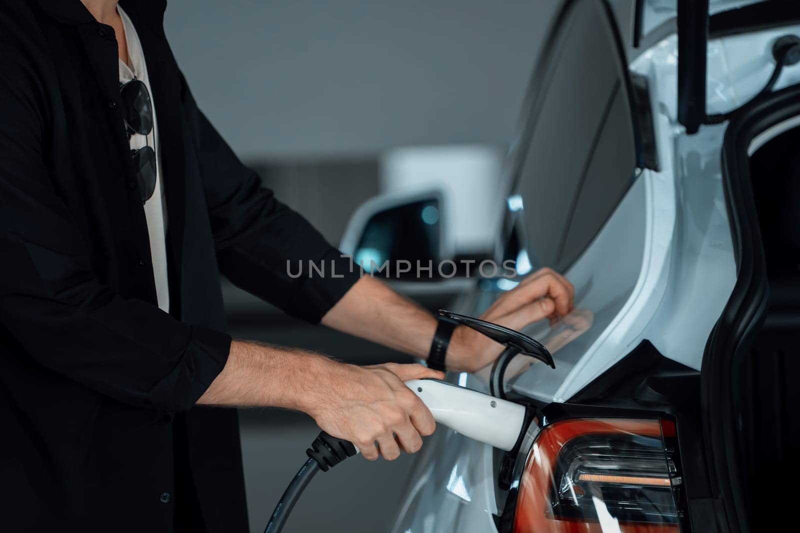 Young man travel with EV electric car to shopping center parking lot charging in downtown city showing urban sustainability lifestyle by green clean rechargeable energy of electric vehicle innards