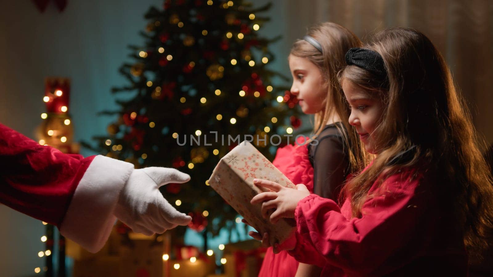 Little sisters receiving gifts from Santa Claus .