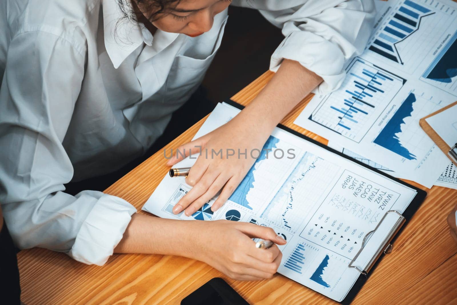 Diverse group of business analyst team analyzing financial data report paper on office table. Chart and graph dashboard by business intelligence analysis for strategic marketing planning Meticulous