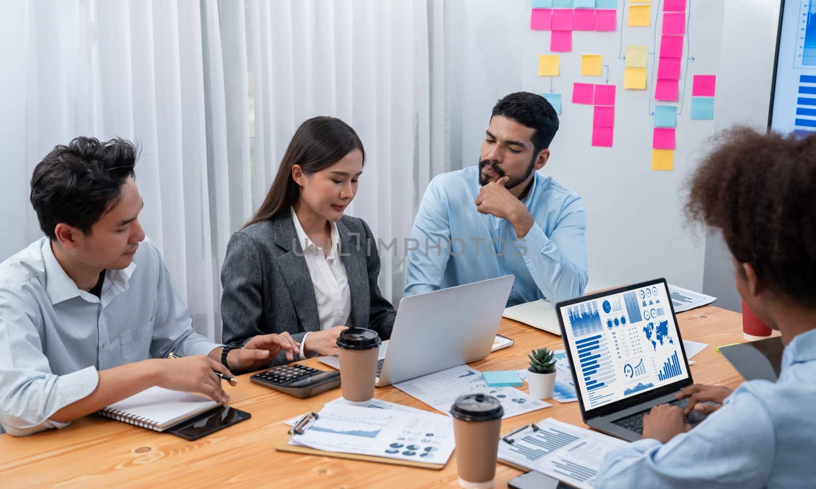 Multiracial analyst team use BI Fintech software to analyze financial data on meeting table. Financial dashboard data display on laptop screen with analyzed chart for marketing indication. Concord