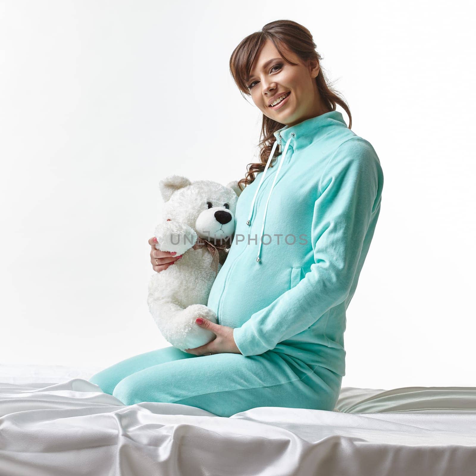 Happy expectant mother posing in casual clothes with toy