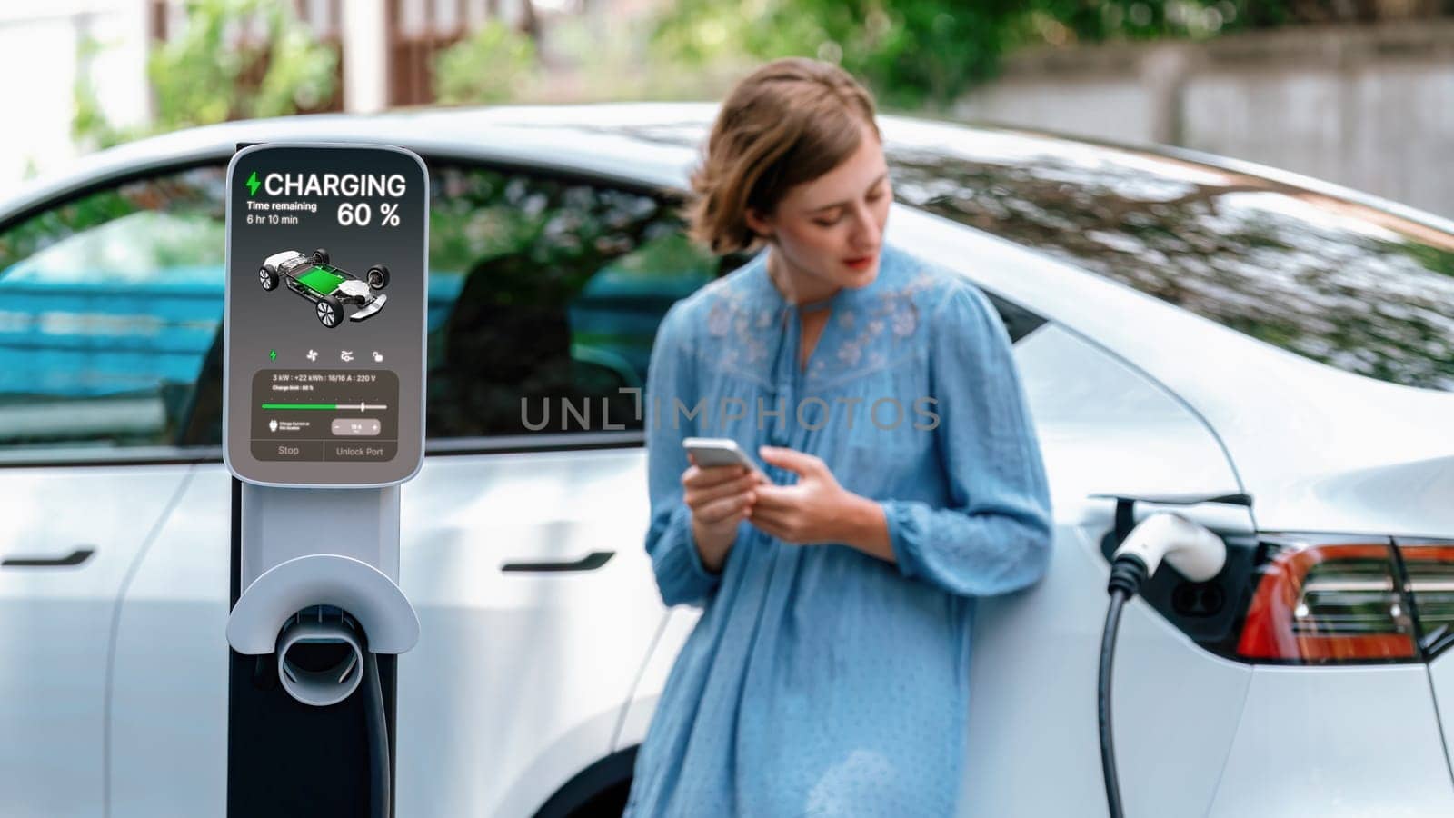 Electric vehicle recharging battery from home EV charging station using alternative energy with net zero emission on blurred background of young girl charging her car before vacation travel. Perpetual