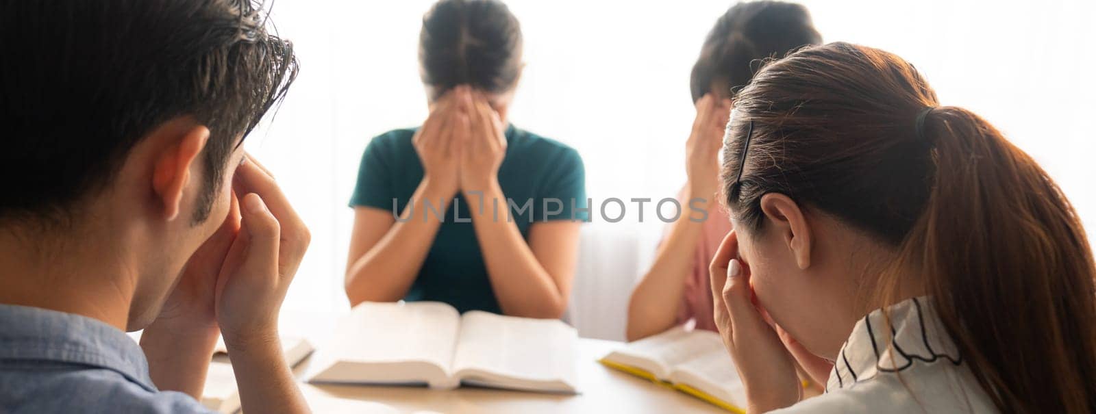 Cropped image of Group of believer hand praying together while raising hand at wooden church on bible book. Prayers hold hand together faithfully. Concept of hope, religion, faith, god blessing. Burgeoning.