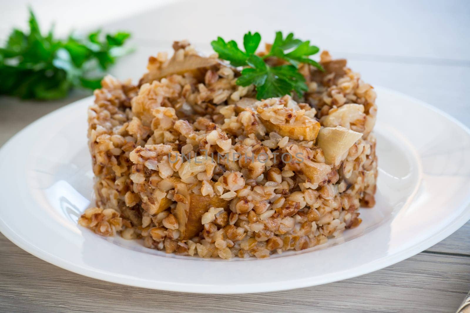cooked buckwheat boiled with mushroom filling in a plate on a wooden table.