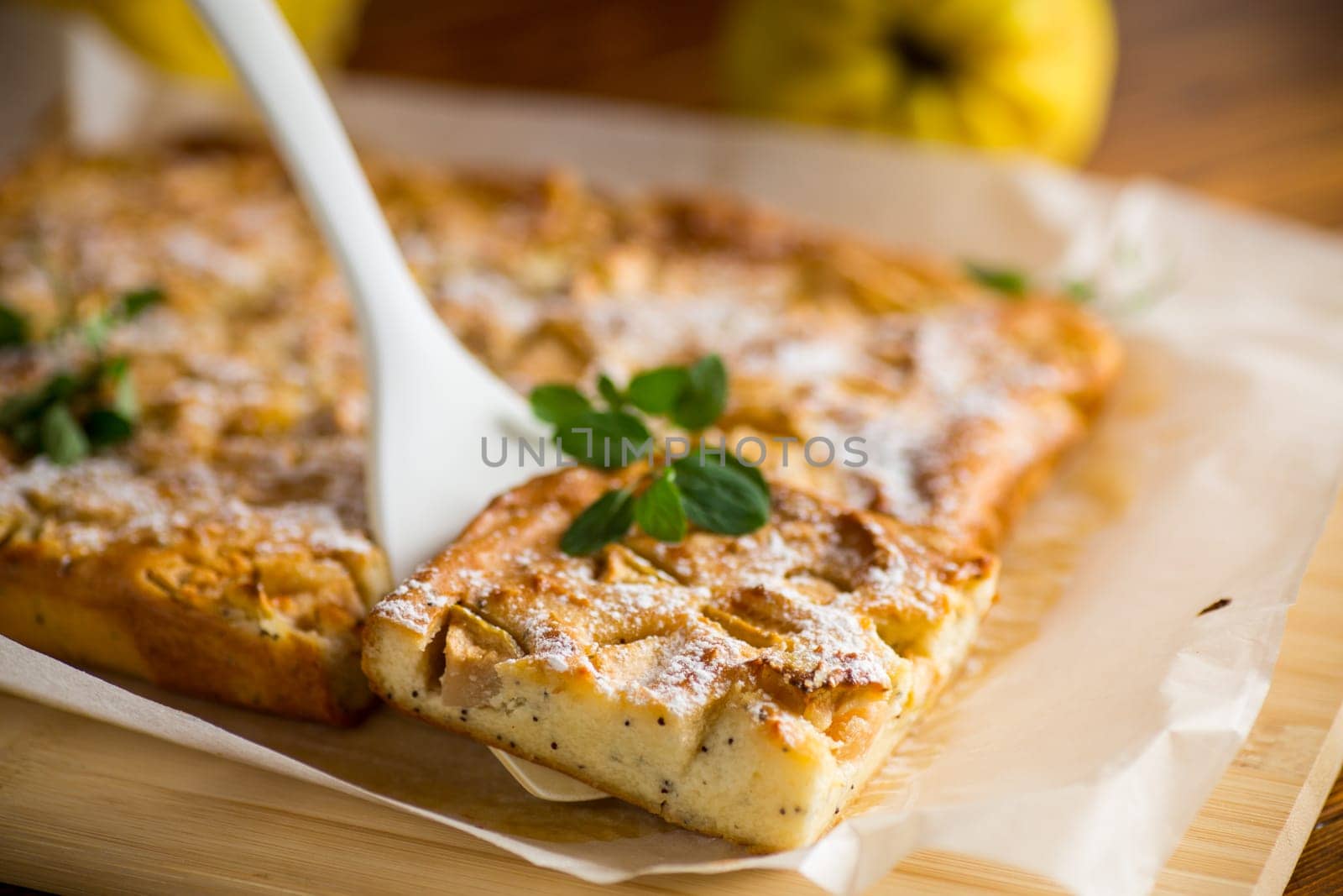 prepared curd semolina pie with quince inside and covered with powdered sugar on a wooden board.
