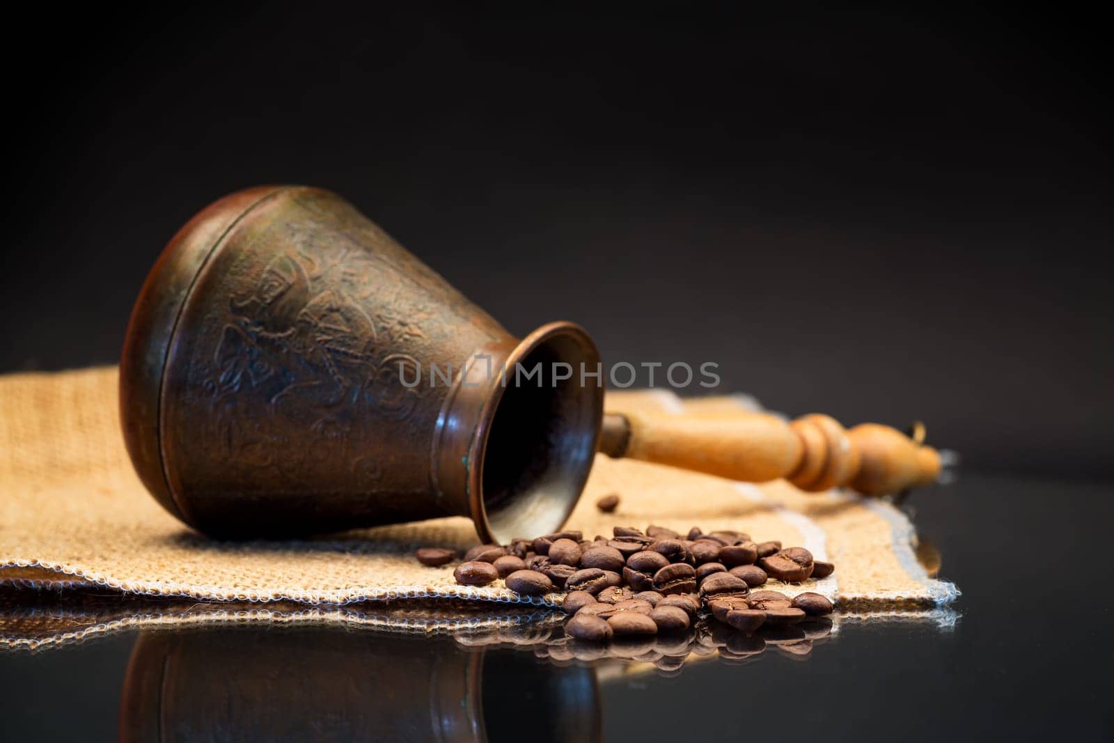 natural coffee beans, Turkish coffee pot on burlap, isolated on a black background