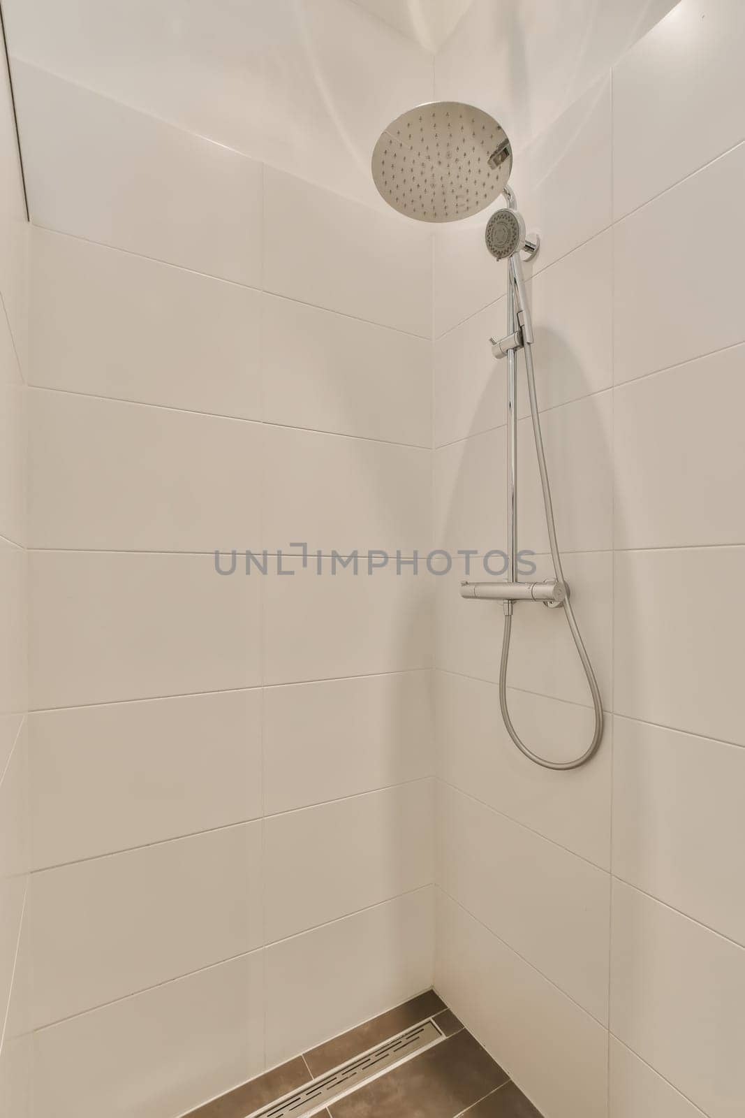 a shower with a shower head in a white bathroom by casamedia