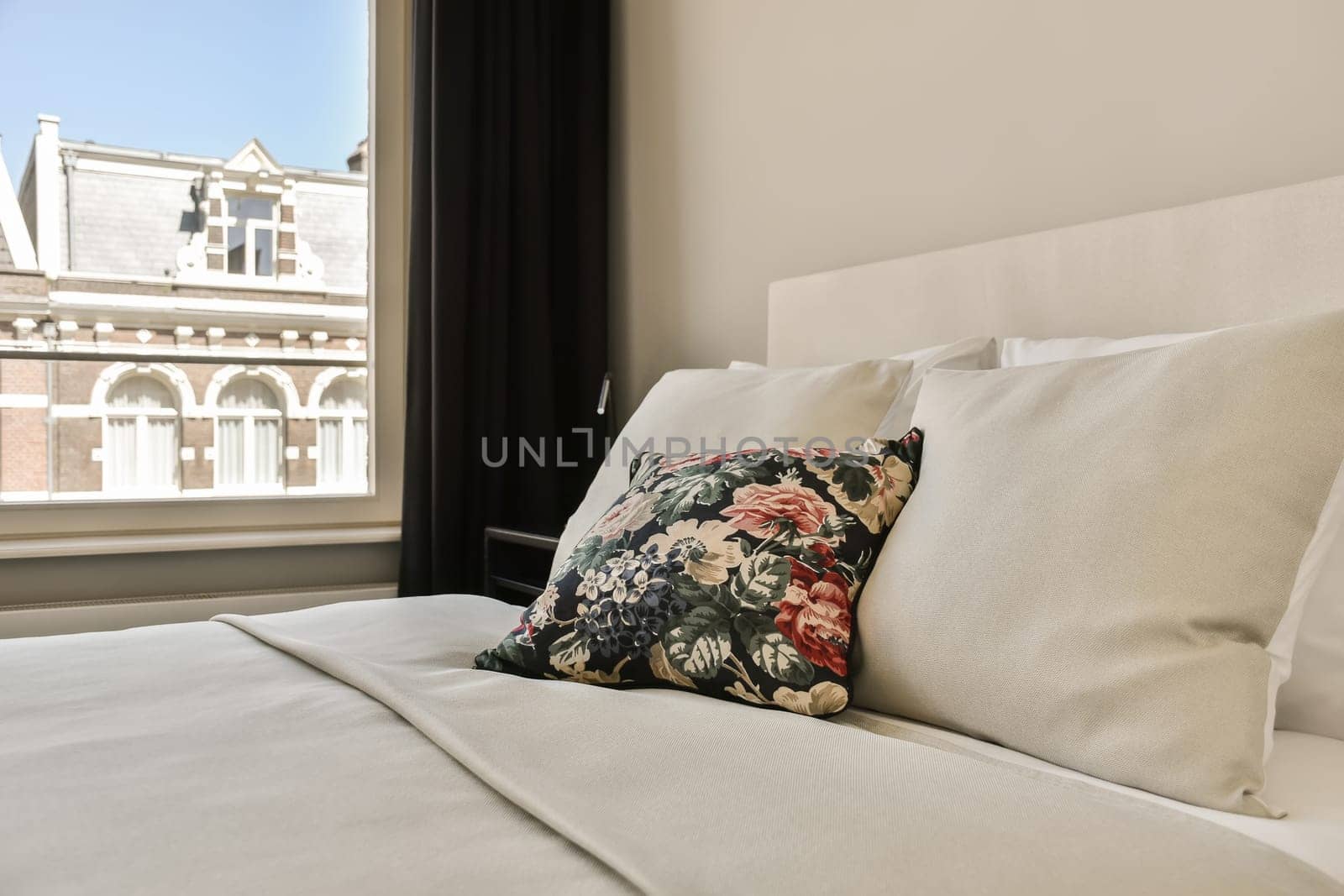 a bed with white sheets and pillows in front of a large window looking out onto the cityscapea
