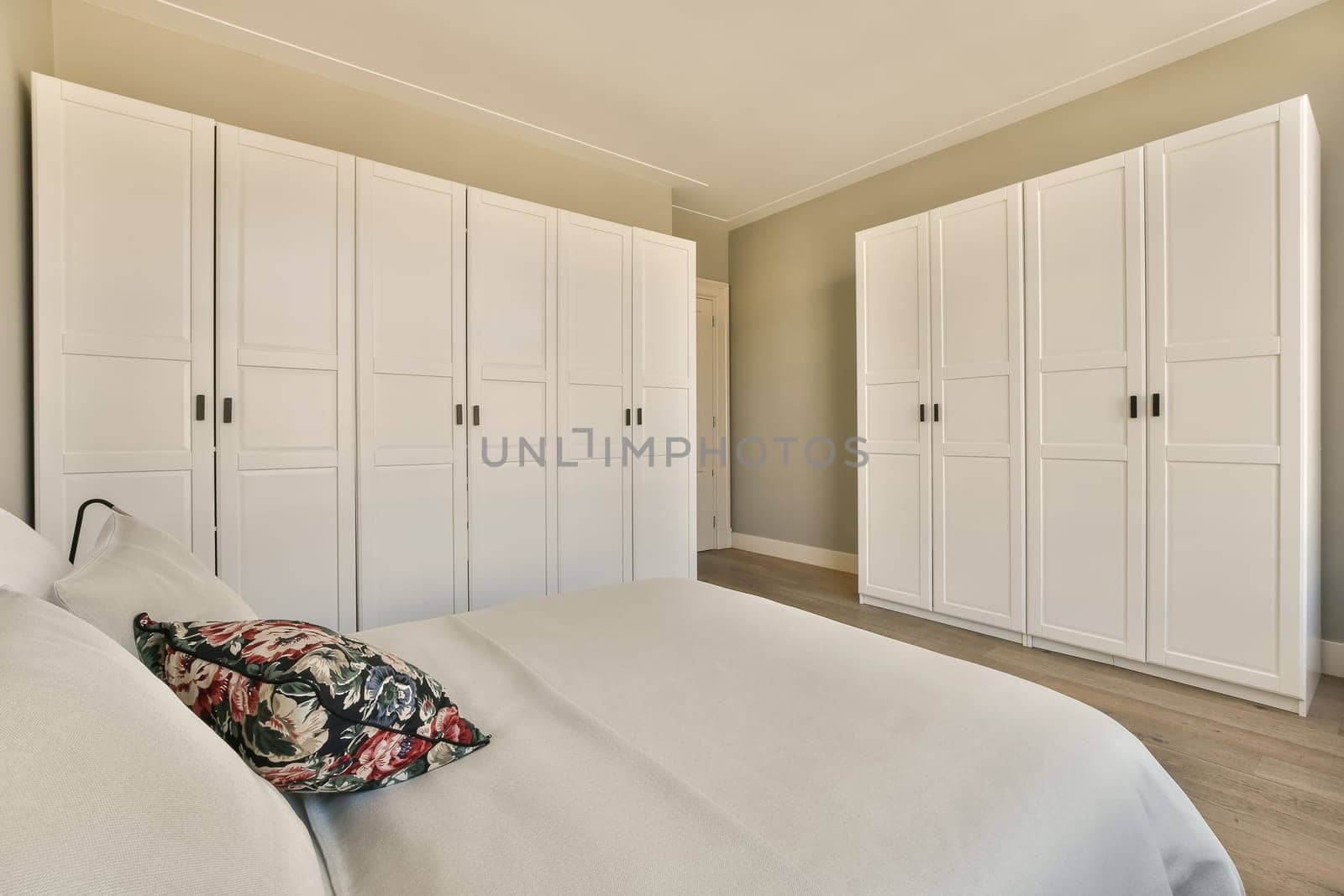 a bedroom with white cabinets and a large bed by casamedia