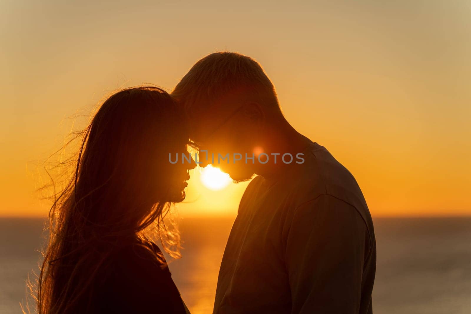 At sunset, a couple shares a tender embrace on the beach, basking in the tranquility of their holiday and the beauty of nature