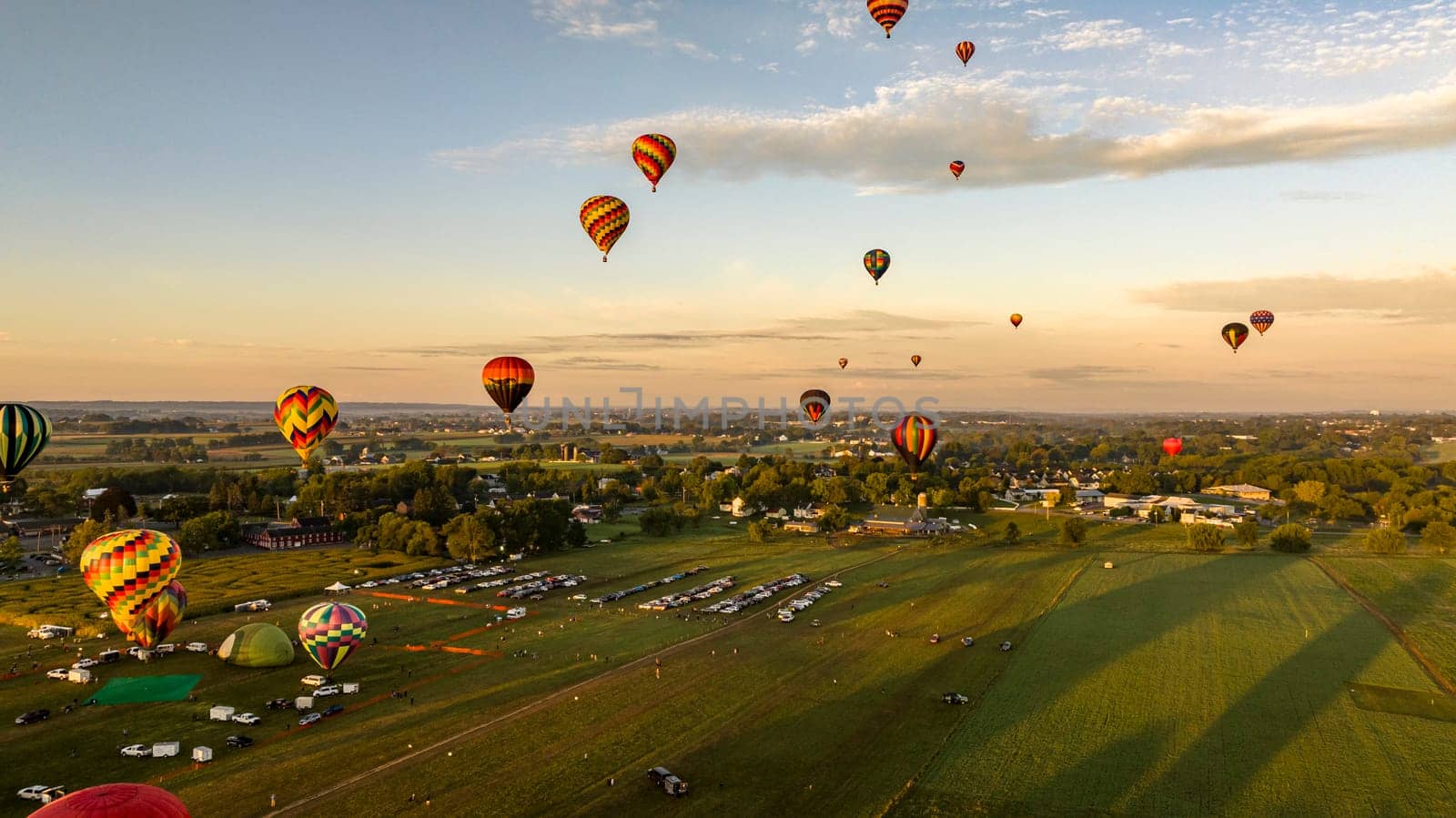An Aerial View of Multiple Hot Air Balloons Floating Up During a Morning Launch on a Sunny Summer Day