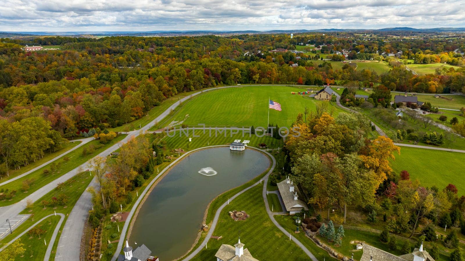 An Aerial View of Fall Countryside of Sun and Color with a Pond and American Flag on a Sunny Autumn Day