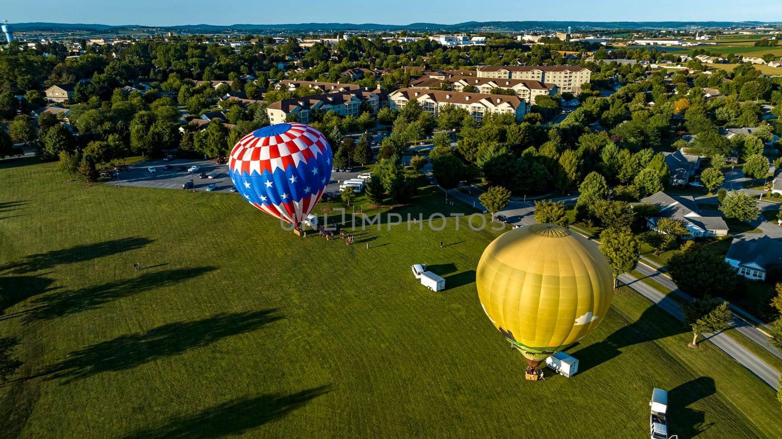 An Aerial View of Two Hot Air Balloons Setting Up to Launch on a Field in a Community, on a Sunny Summer Afternoon