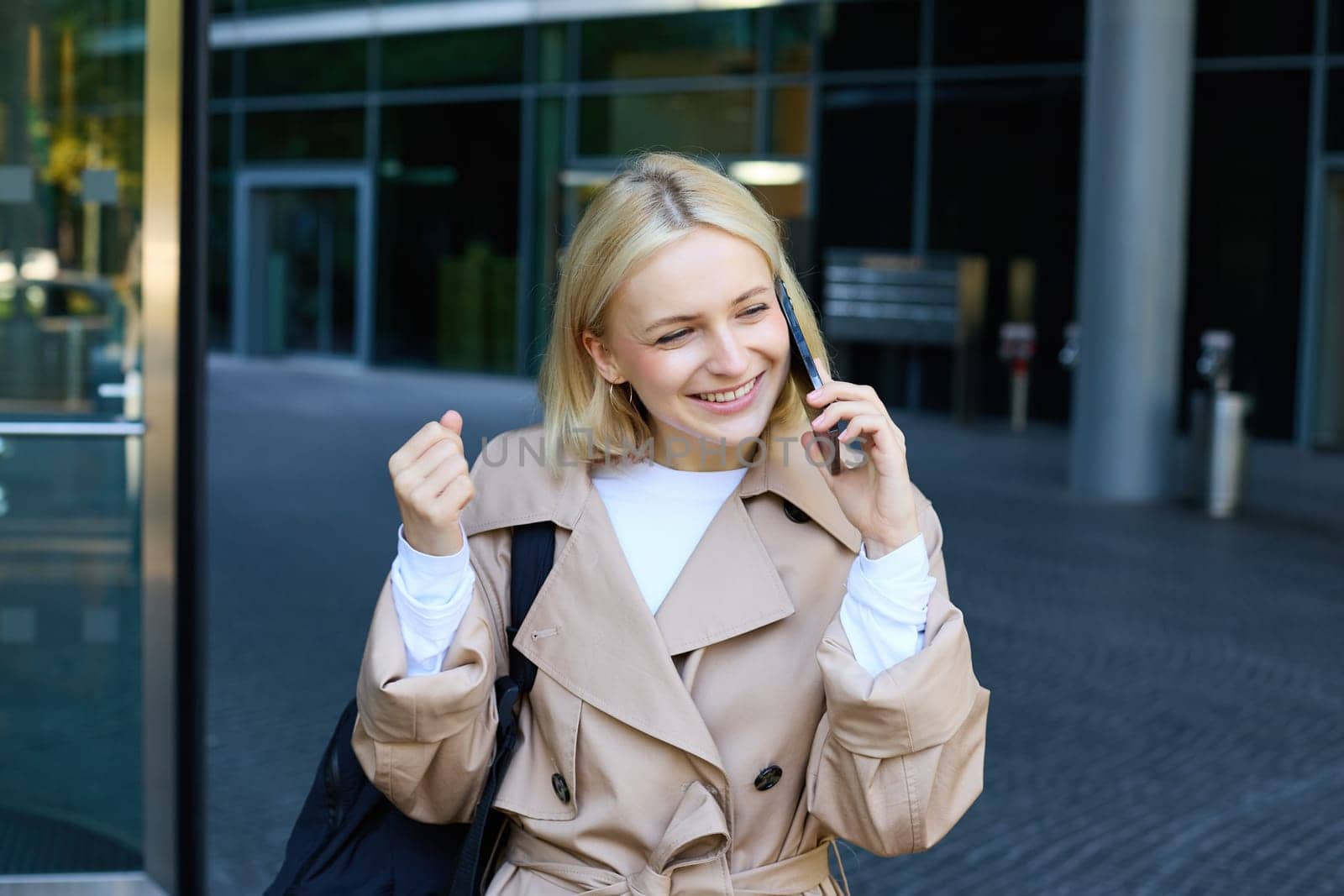 Close up portrait of young blond woman, walking on street and talking on mobile phone, chatting with friend on smartphone. Lifestyle and people concept