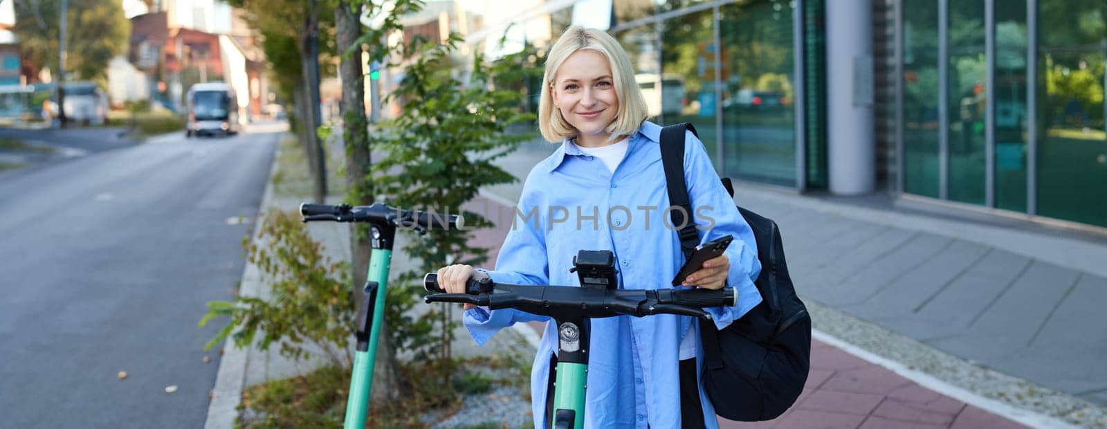 Woman Scanning QR Code on Handlebar of Shared Electric Scooter. Close up of Female Hand Holding Smartphone Unlocking Green E-Scooter in Street.
