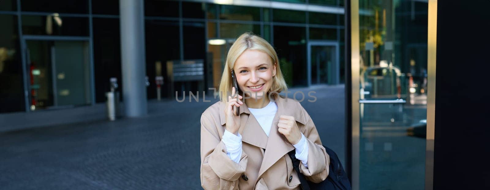 Close up portrait of young blond woman, walking on street and talking on mobile phone, chatting with friend on smartphone. Lifestyle and people concept