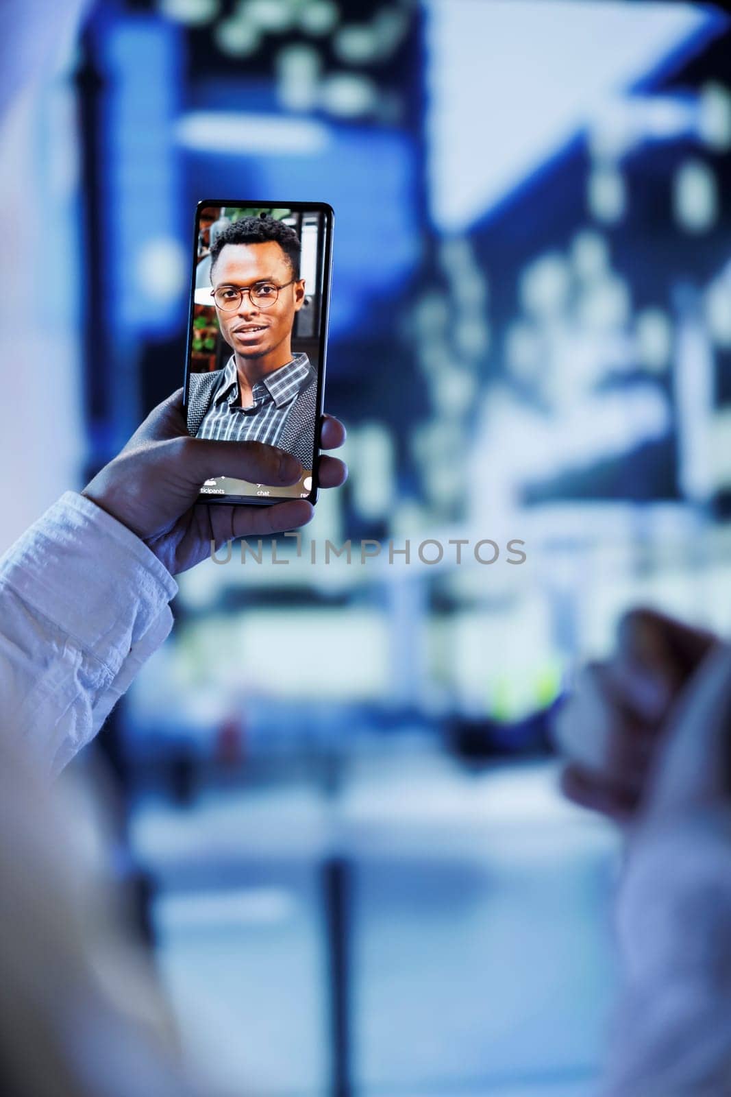 Woman in videocall with husband while walking around city streets at night, close up. Citizen using smartphone to show spouse surroundings in dimly illuminated urban center in blurry background