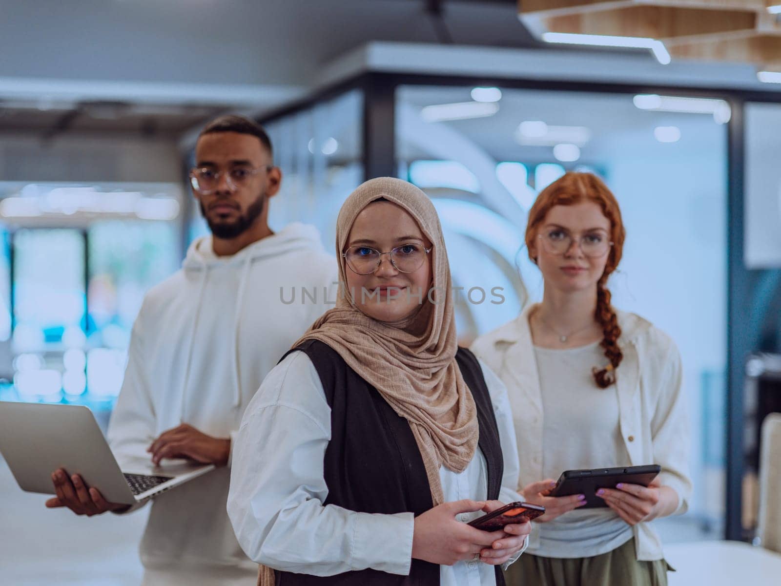 A diverse group of young business individuals is captured in a professional portrait at a modern office, reflecting their teamwork, ambition, and creativity in a vibrant and dynamic corporate setting.