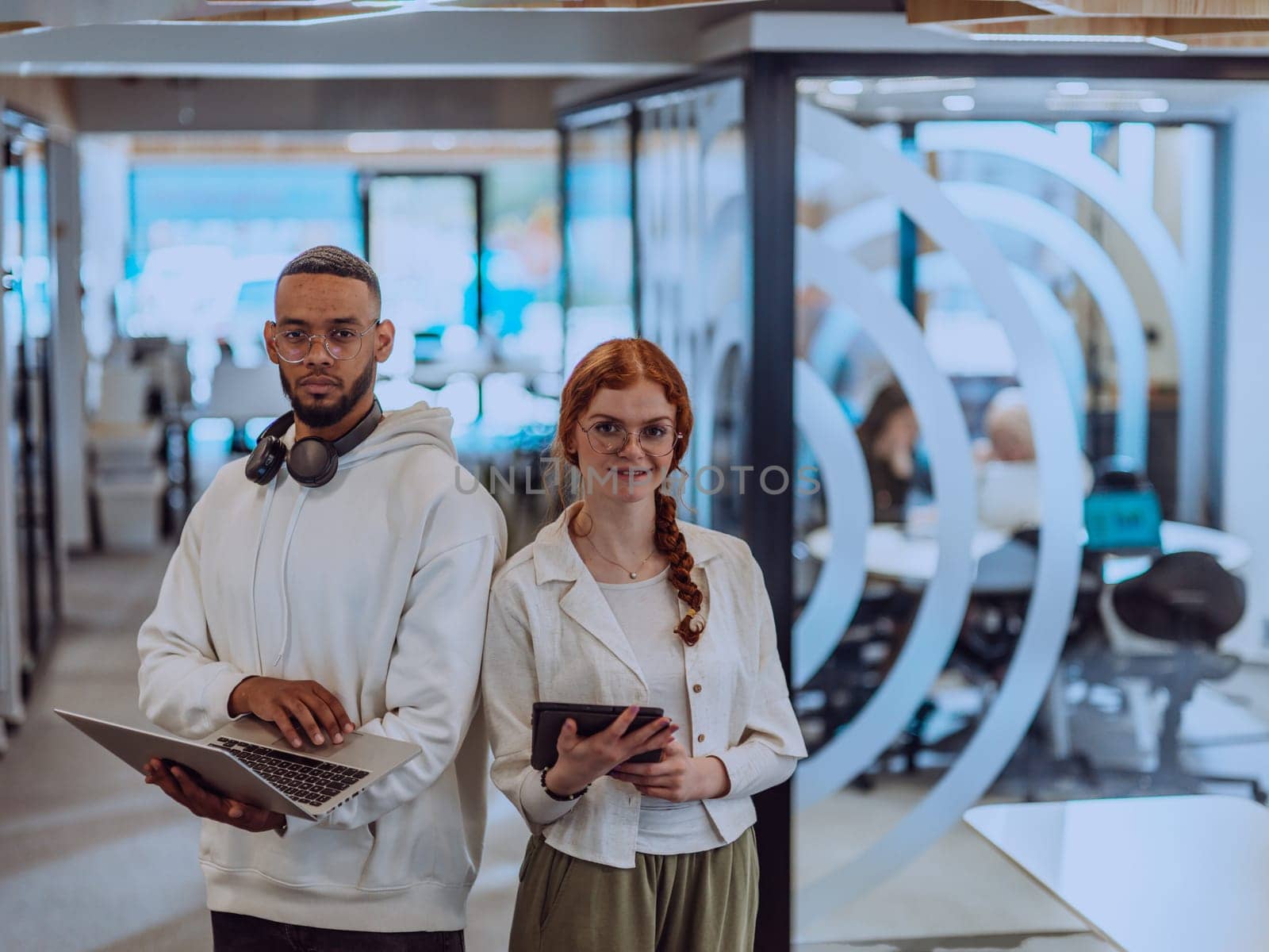 In a modern office African American young businessman and his businesswoman colleague, with her striking orange hair, engage in collaborative problem-solving sessions.