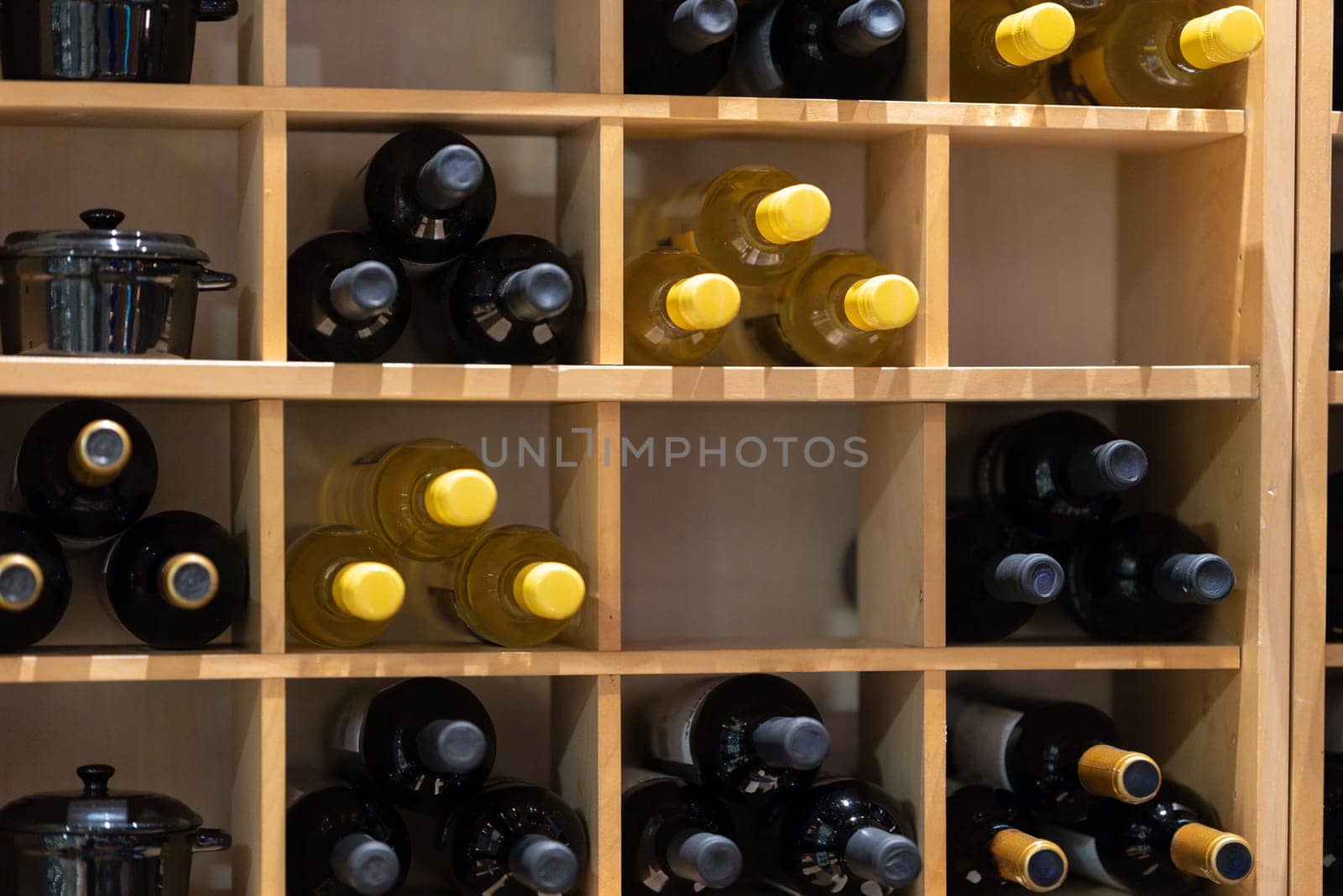 A stack of wine bottles in cabinet shelving in restaurant by Studia72