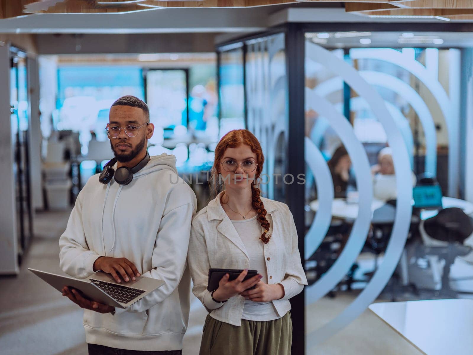 In a modern office African American young businessman and his businesswoman colleague, with her striking orange hair, engage in collaborative problem-solving sessions.