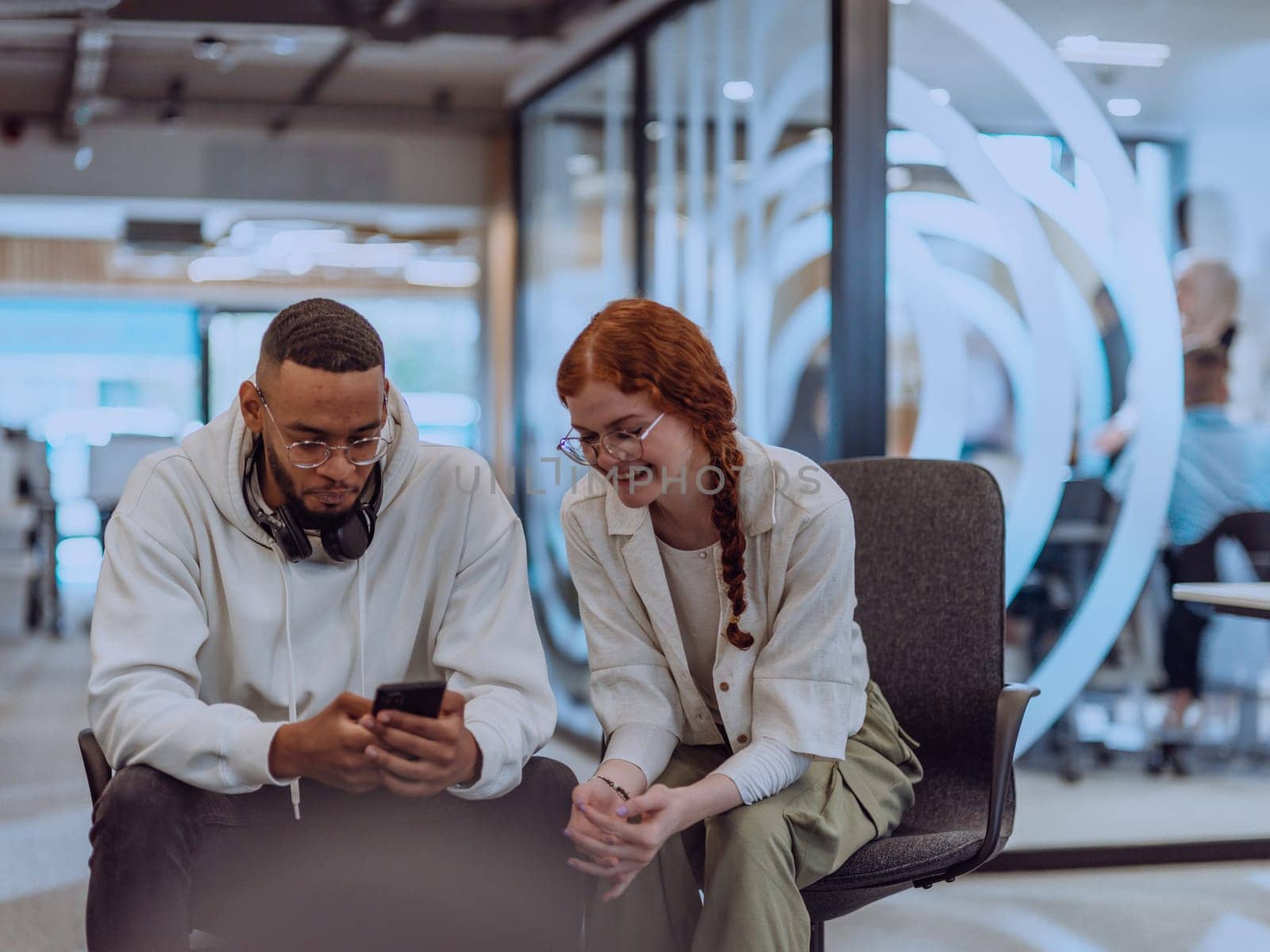 In a modern office African American young businessman and his businesswoman colleague, with her striking orange hair, engage in collaborative problem-solving sessions by dotshock