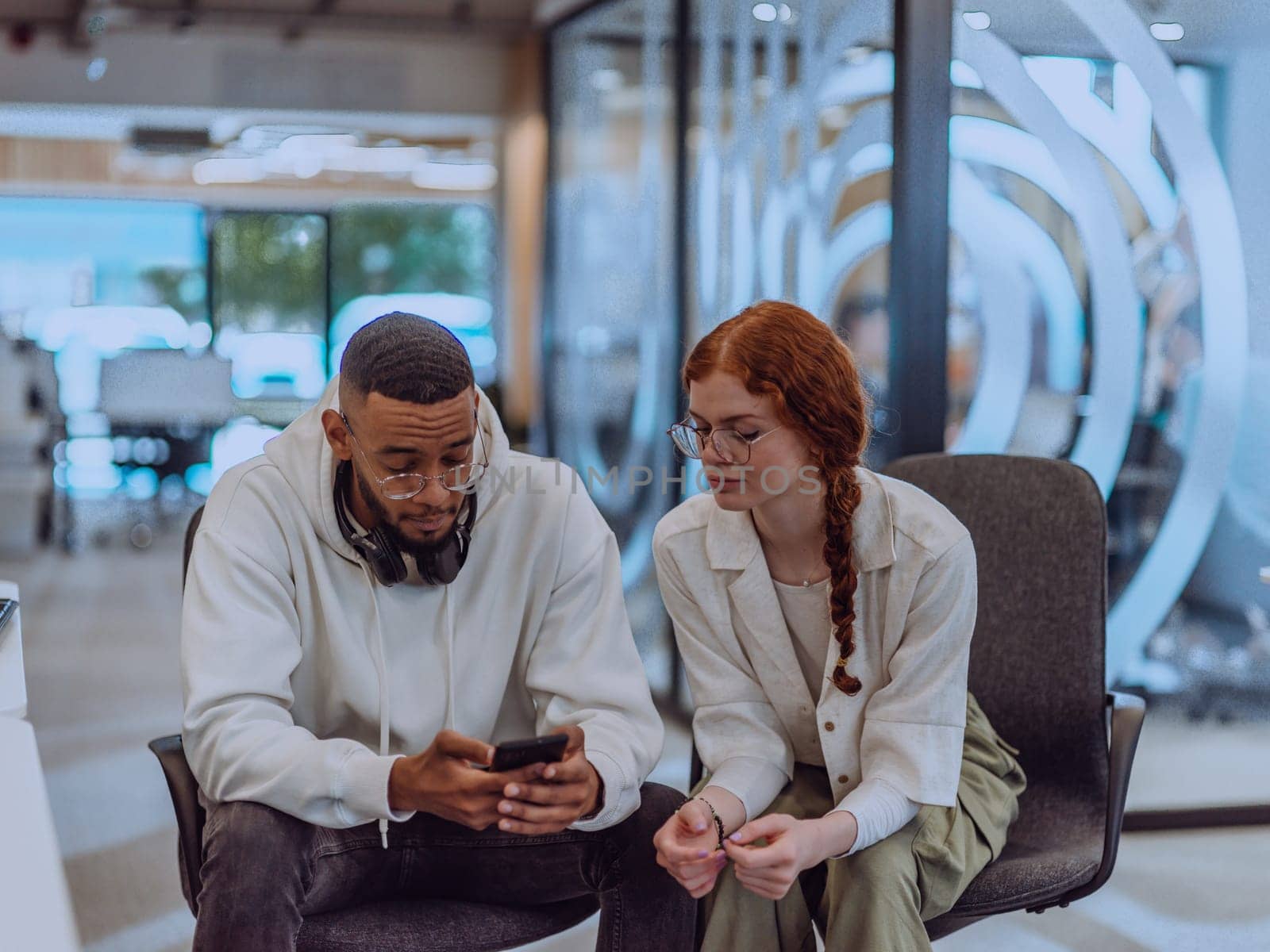 In a modern office African American young businessman and his businesswoman colleague, with her striking orange hair, engage in collaborative problem-solving sessions by dotshock