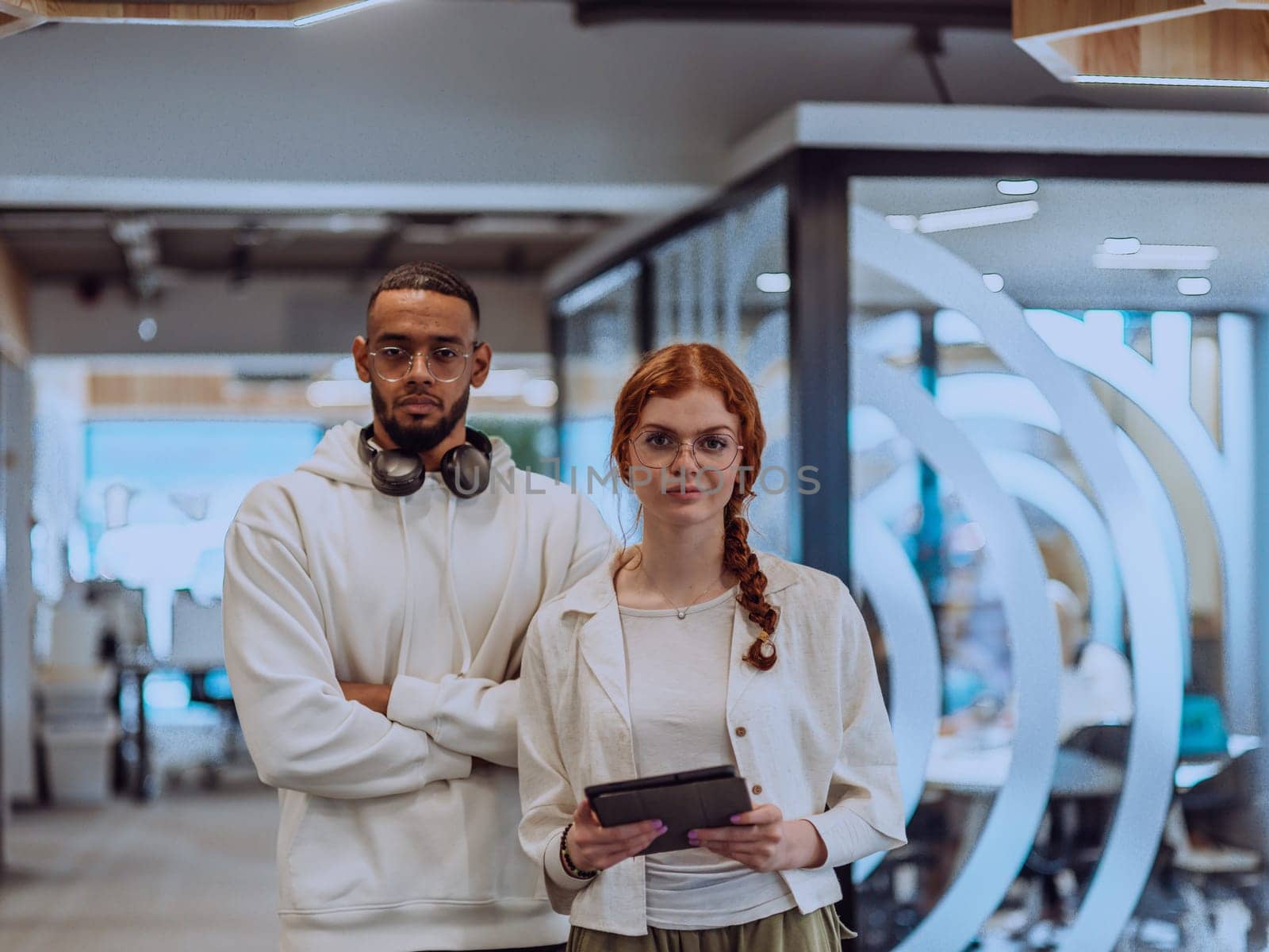 In a modern office African American young businessman and his businesswoman colleague, with her striking orange hair, engage in collaborative problem-solving sessions.