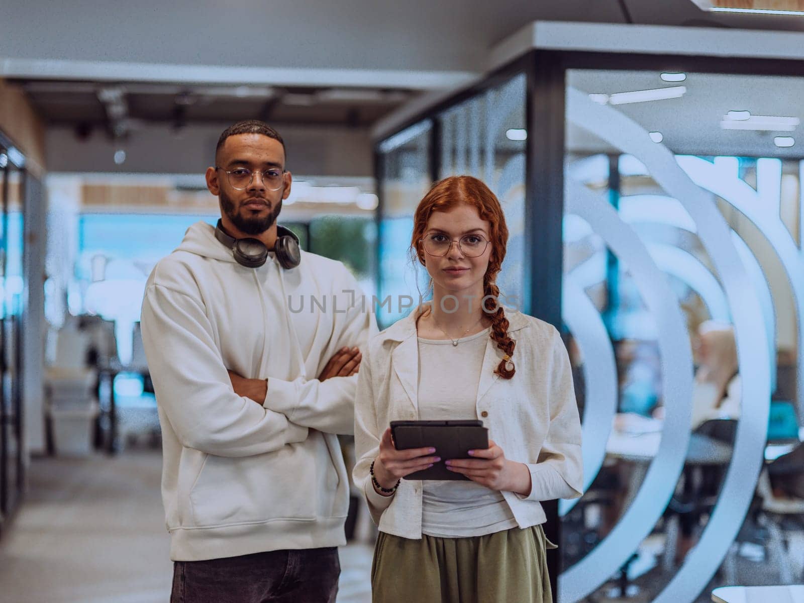 In a modern office African American young businessman and his businesswoman colleague, with her striking orange hair, engage in collaborative problem-solving sessions.