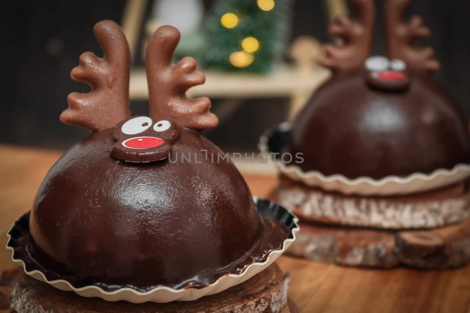 Two chocolate deer on wooden cuts and on a tray with christmas decoration on the table, side view close-up.