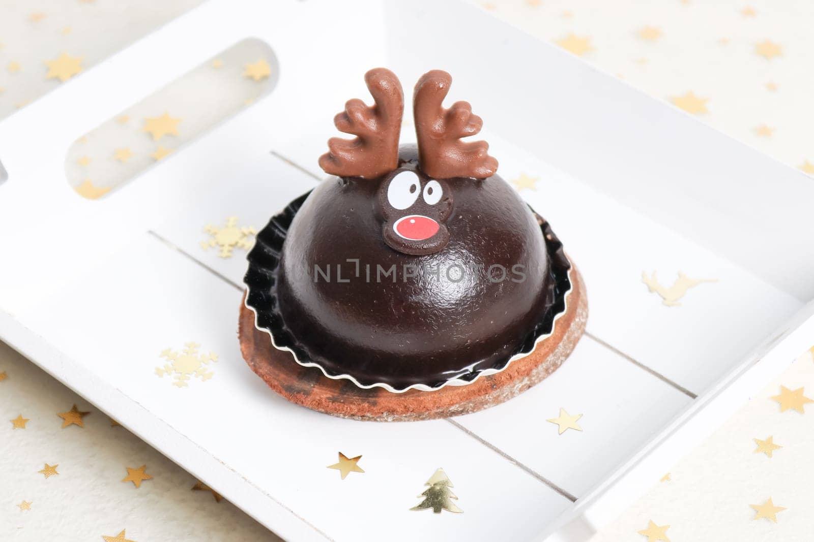 One chocolate deer cake in a white wooden tray on the table, side view close-up.