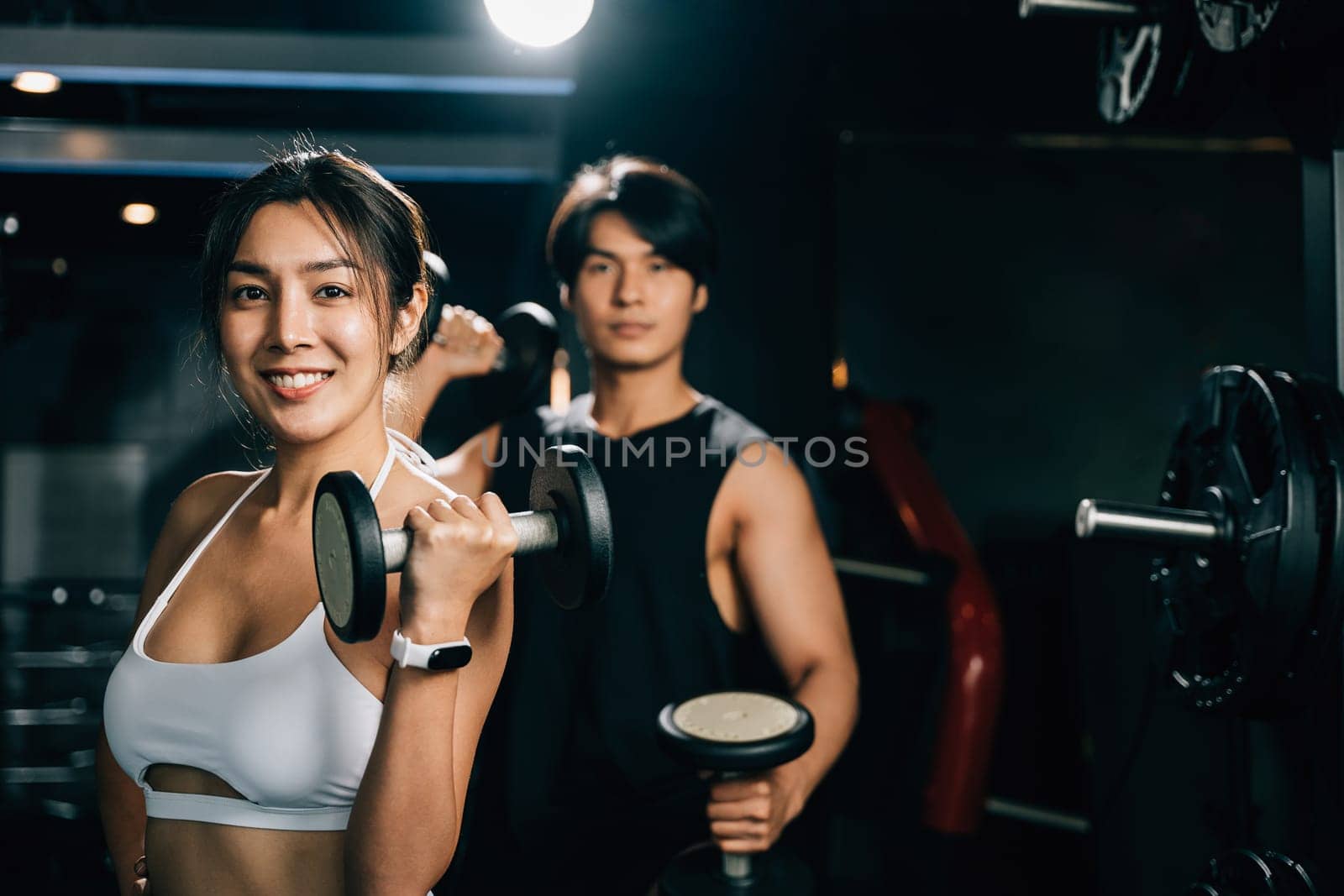 Portrait strong and athletic Asian man and woman, working out in a gym with barbells by Sorapop