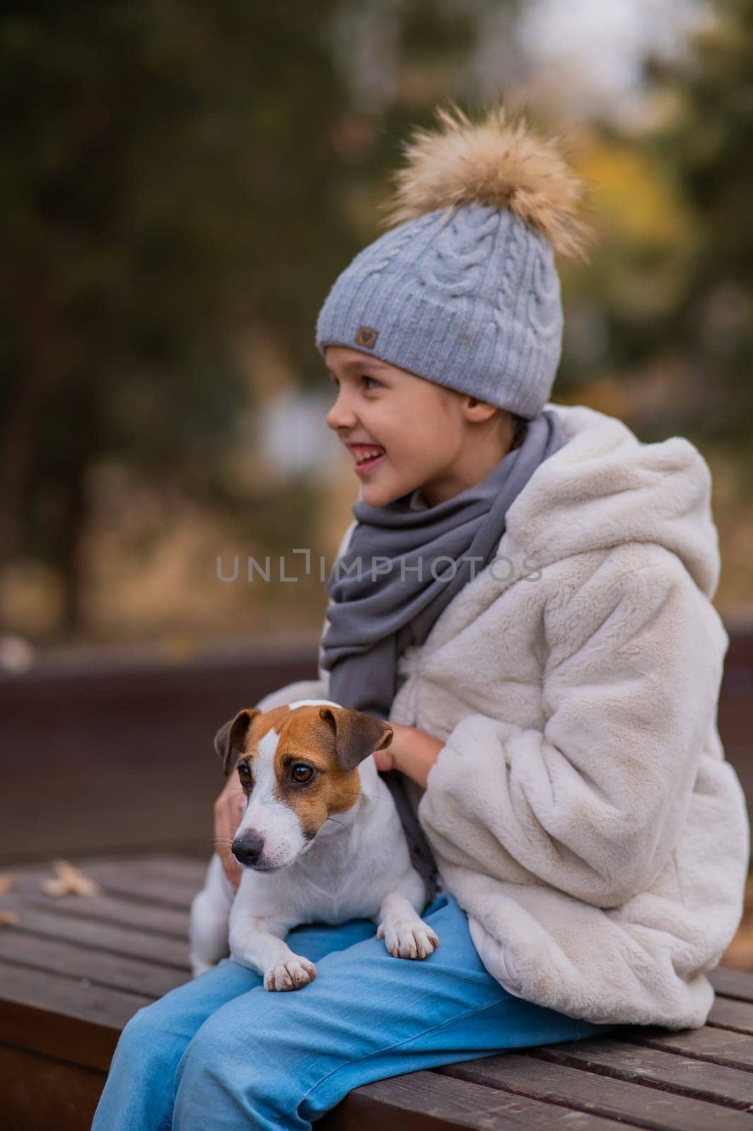 Caucasian girl sits on a bench with a dog Jack Russell Terrier for a walk in the autumn park