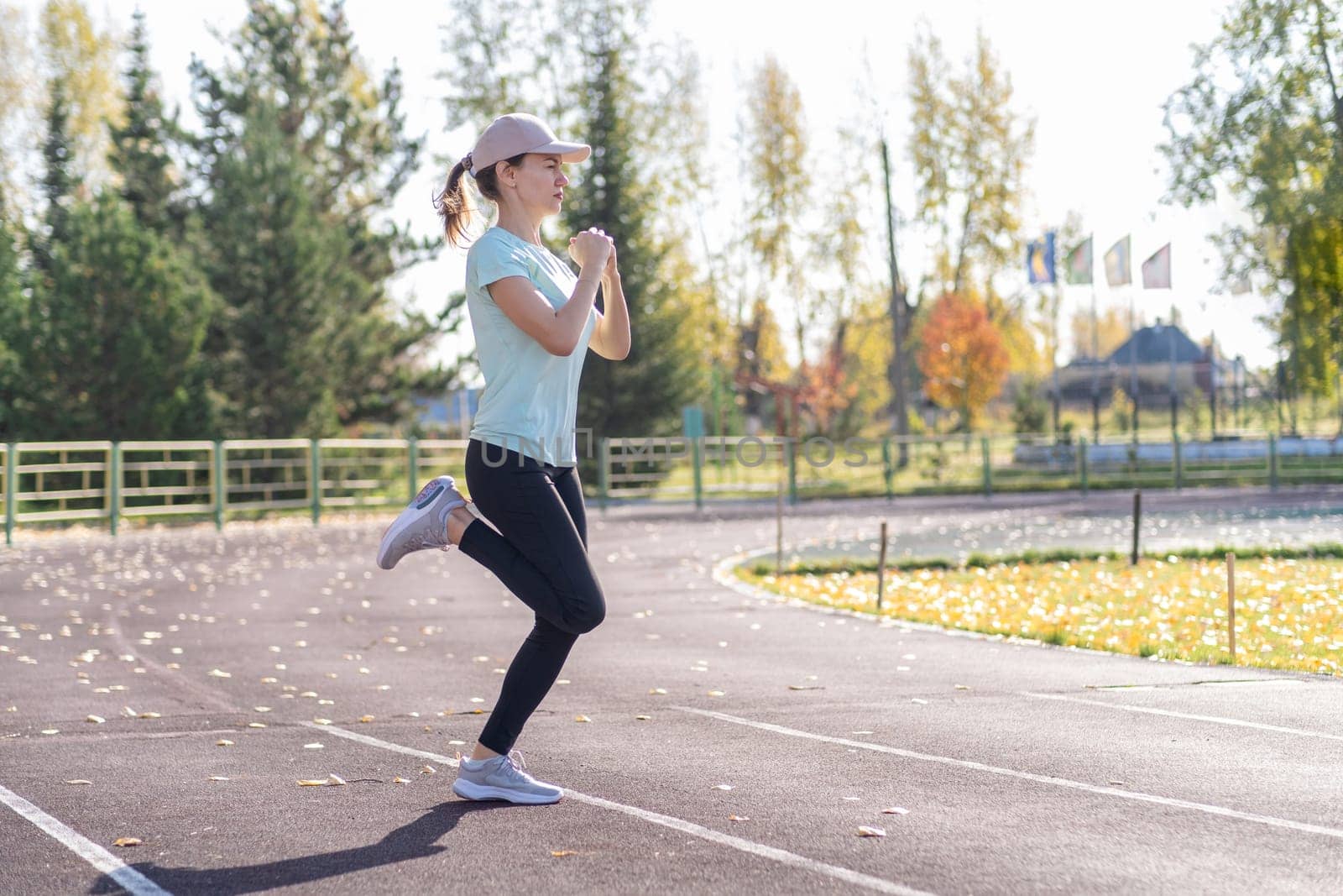 A young beautiful woman in sportswear plays sports at a local stadium. Exercise, jog and exercise at the beginning of the day. Healthy and active lifestyle.