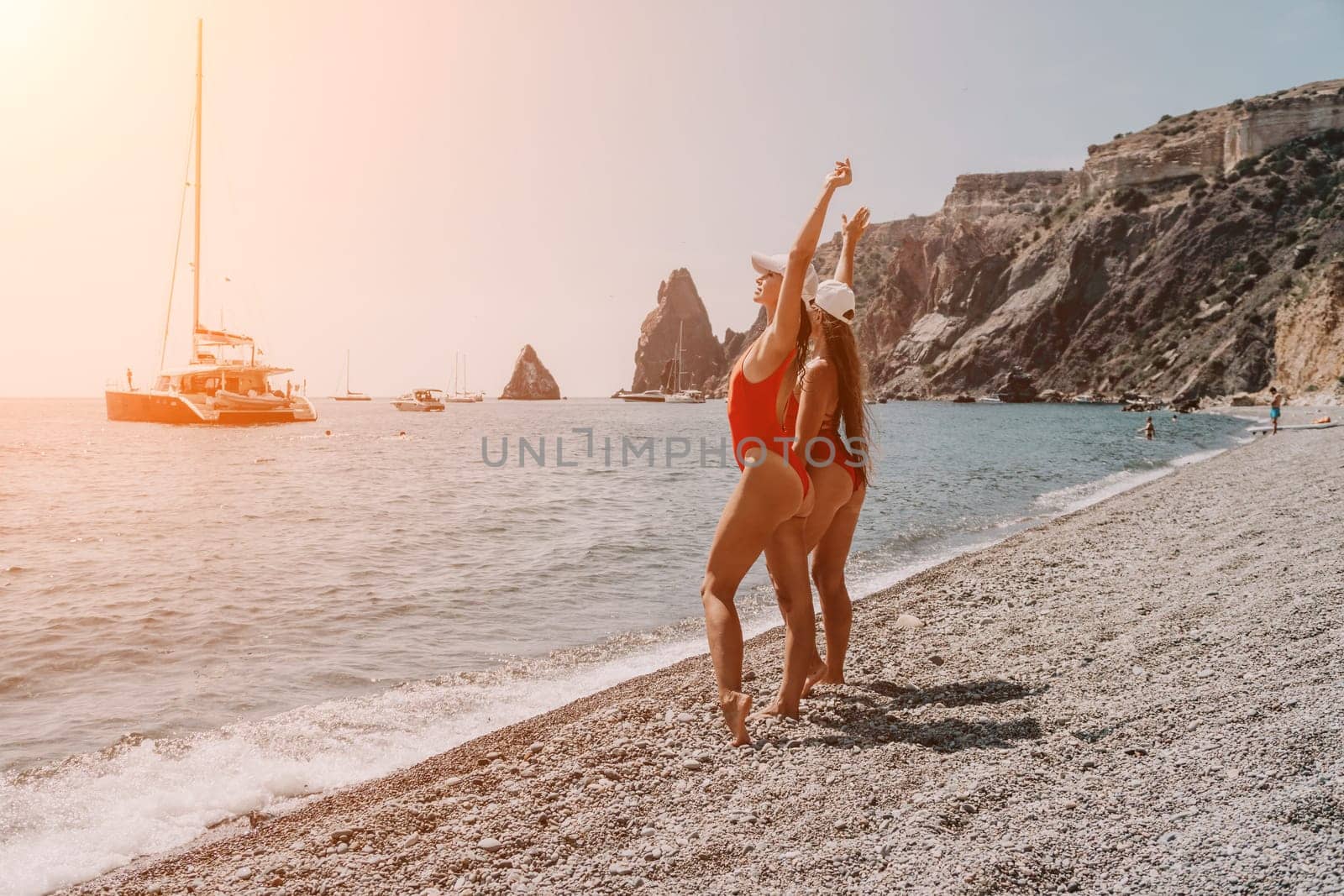 Side view a Young beautiful sensual woman in a mint long dress posing on a volcanic rock high above the sea during sunset. Girl on the nature on overcast sky background. Fashion photo