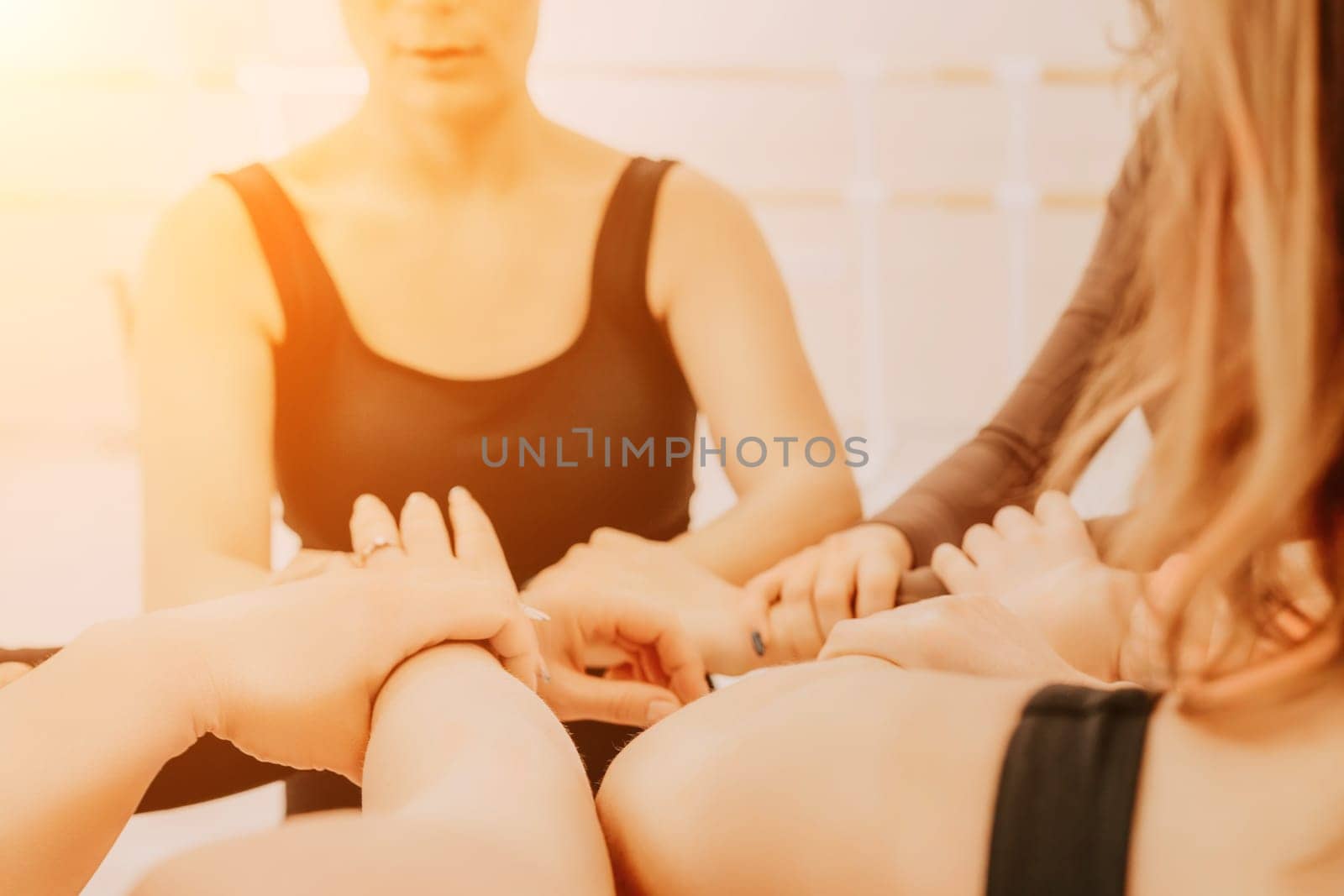 Group of young womans fitness instructor in Sportswear Leggings and Tops, stretching in the gym before pilates, on a yoga mat near the large window on a sunny day, female fitness yoga routine concept.