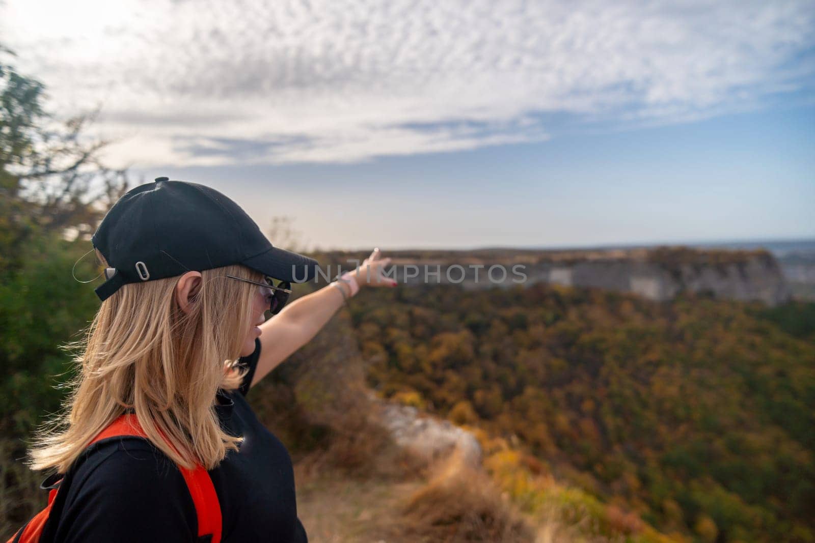 woman on mountain peak looking in beautiful mountain valley in autumn. Landscape with sporty young woman, blu sky in fall. Hiking. Nature.