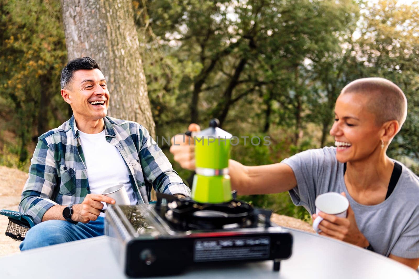 happy couple laughing while having coffee in the countryside, concept of active tourism in nature and outdoor activities