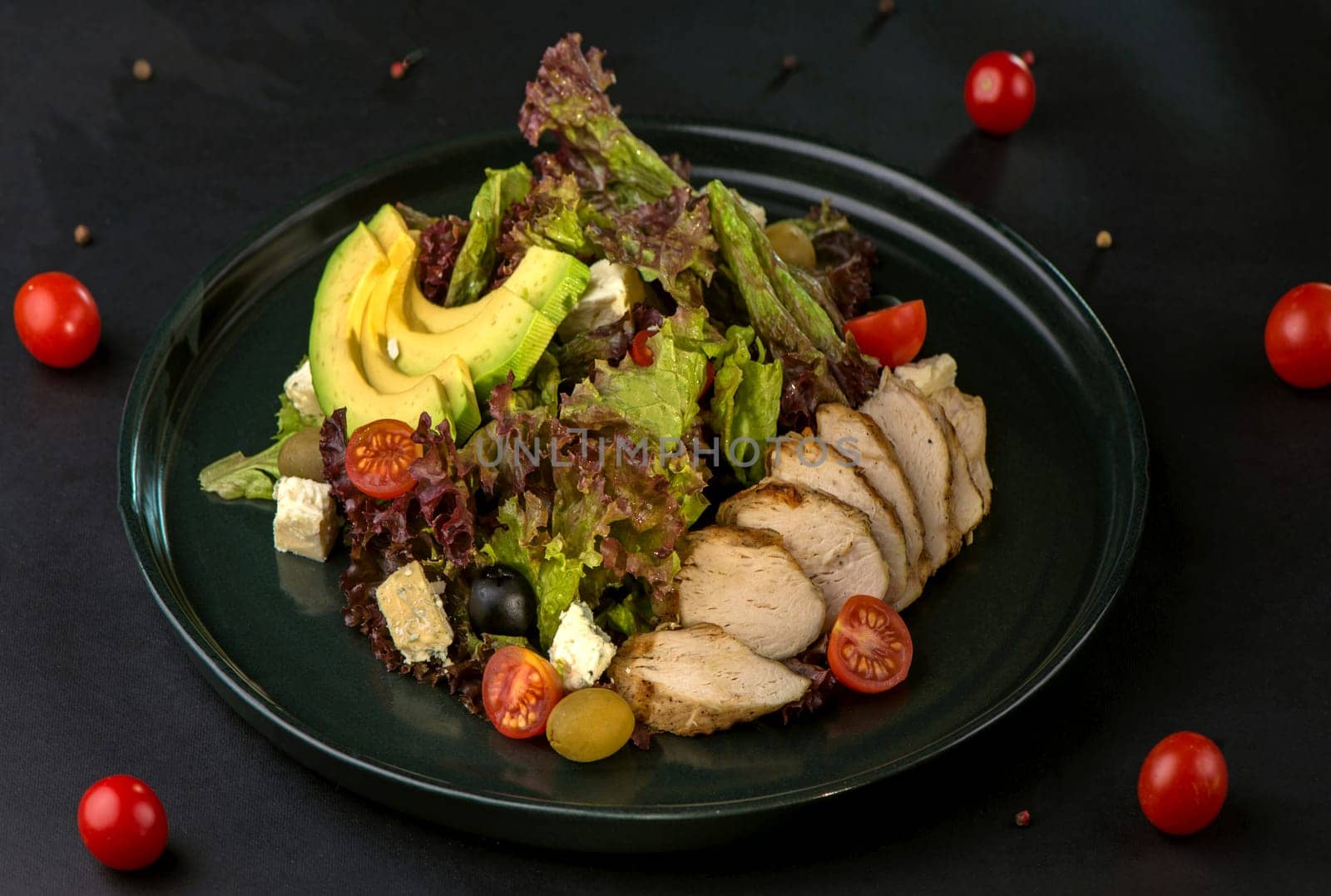 lettuce salad with chicken, avocado and tomatoes on a dark background by aprilphoto