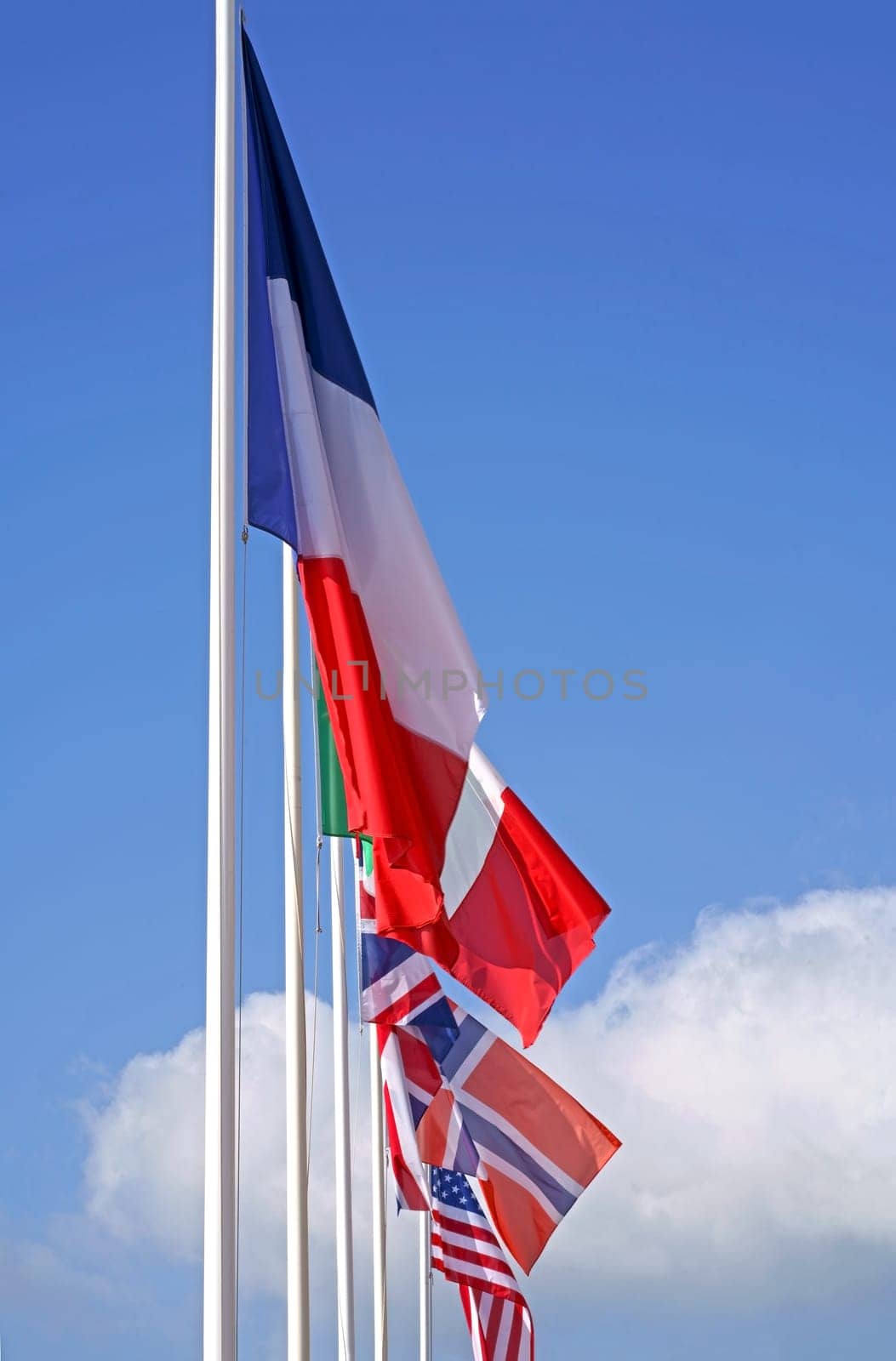 International Flags blowing in the wind against a blue sky. Flags of Italy France Great Britain and America against the blue sky. by aprilphoto