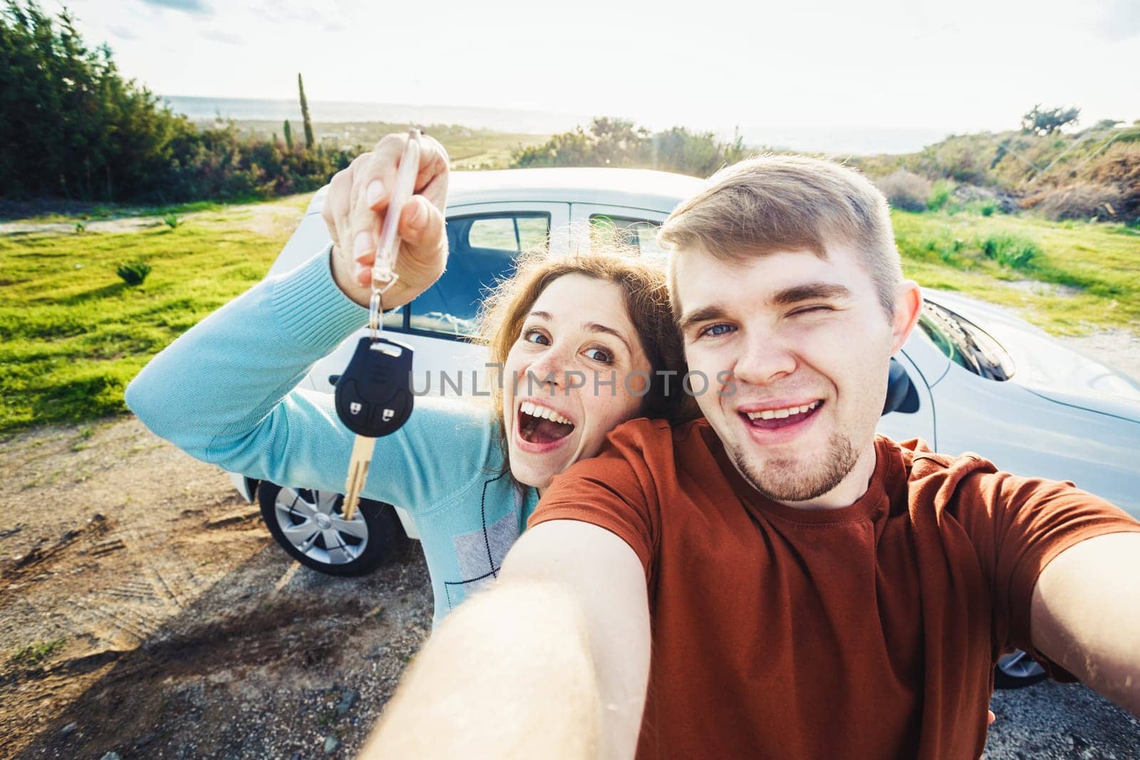 Young happy couple with keys to new car outdoor.