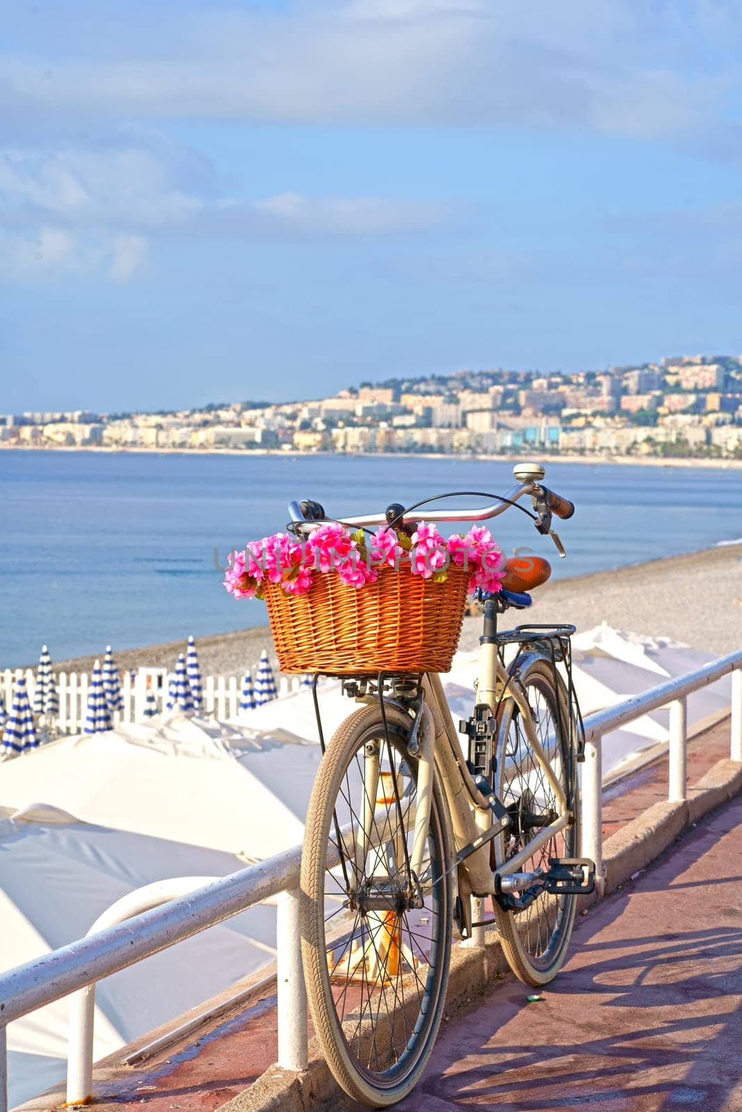 France. Nice. Bicycle with a beautiful basket filled with pink flowers in front of the sea by aprilphoto