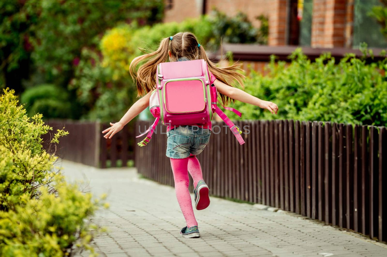 little girl with a backpack run to school. back view